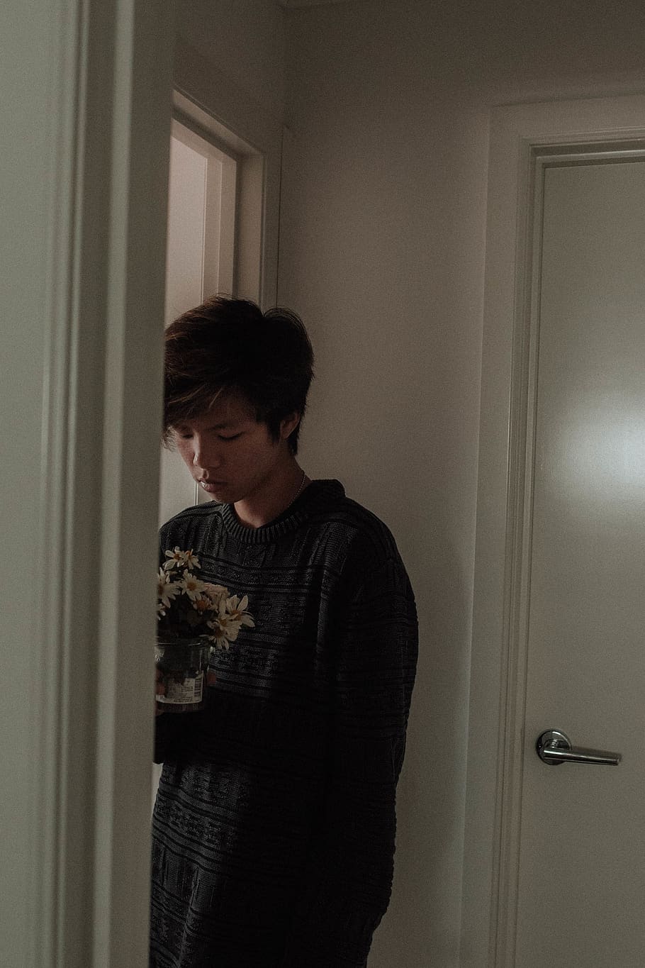 A man in a black sweater holding a vase of flowers - Grunge
