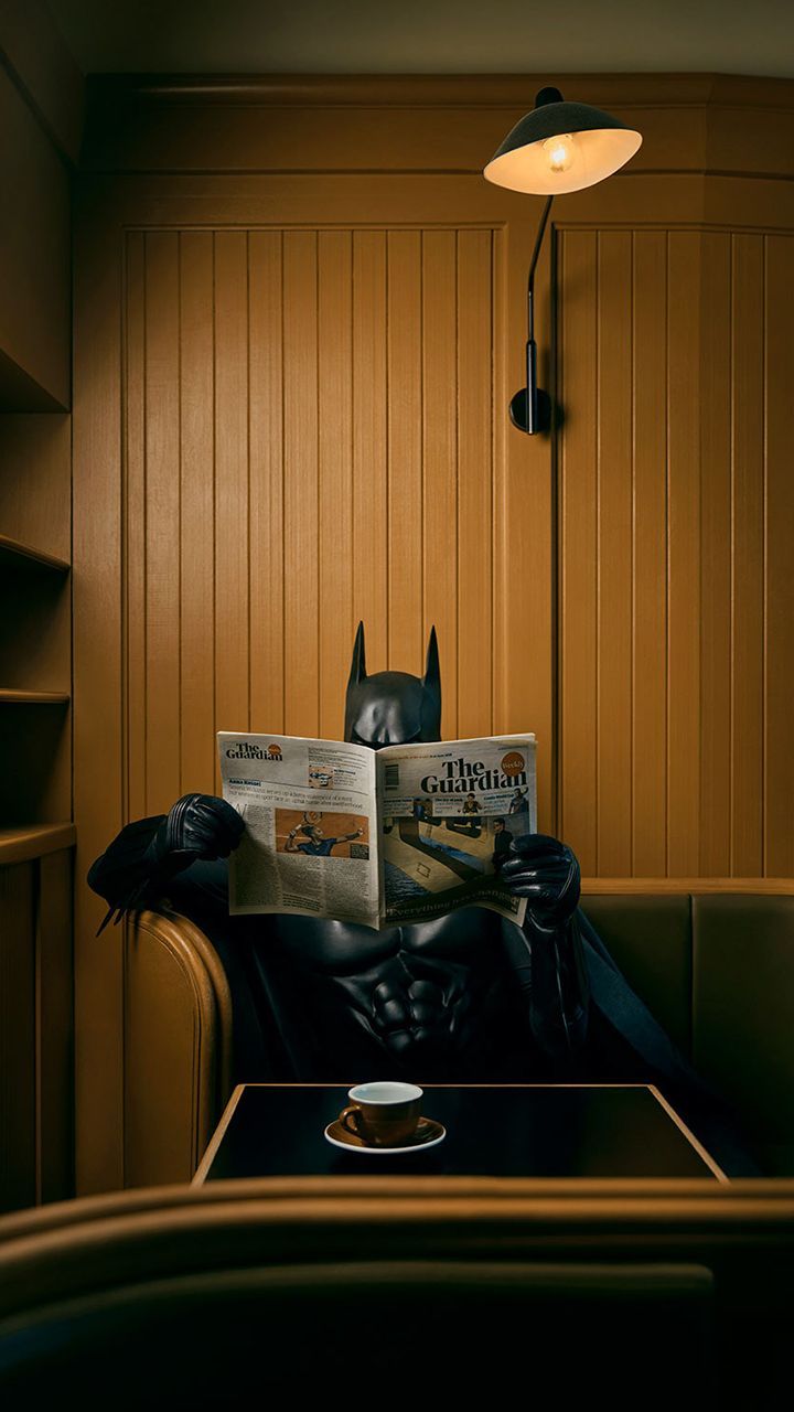 A man sitting in the dark reading his newspaper - Batman