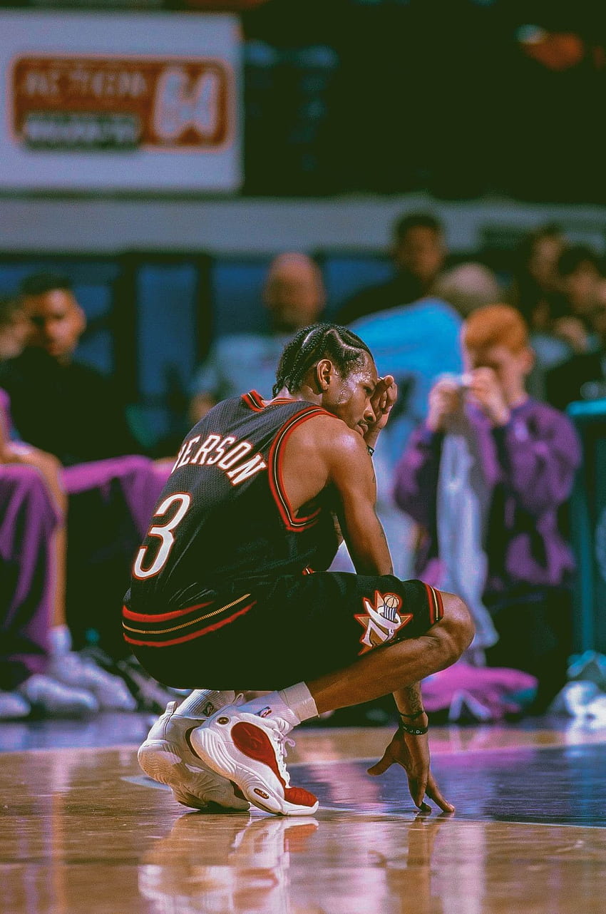 A man is kneeling on the floor of an arena - NBA