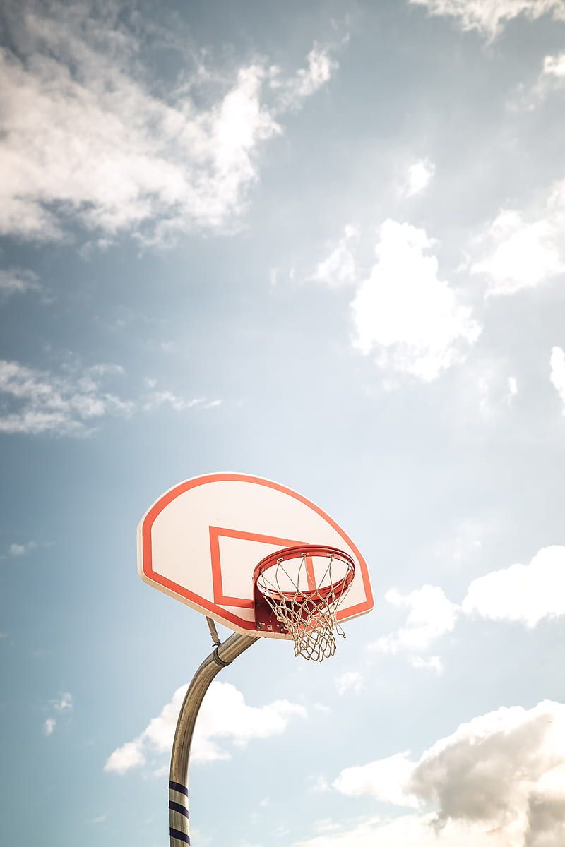 A basketball hoop with a cloudy blue sky in the background - Basketball