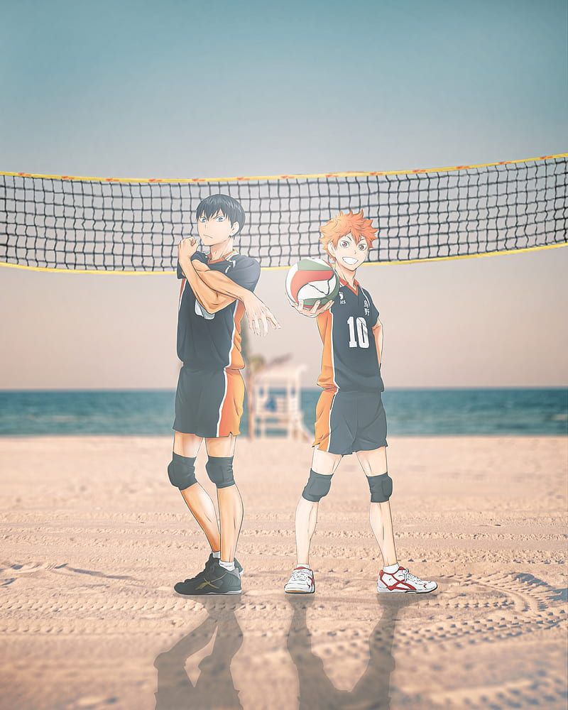 Two people standing on a beach with the ocean in front of them - Volleyball