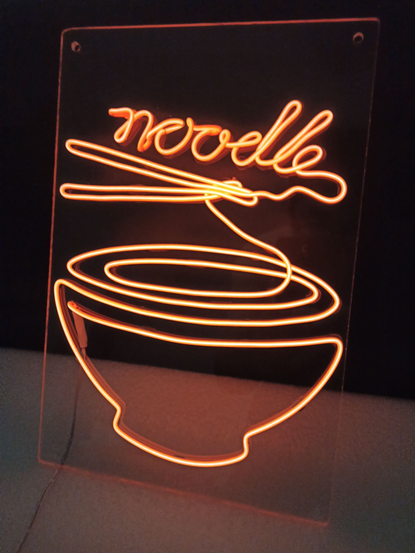 A neon sign of a bowl of noodles - Neon orange