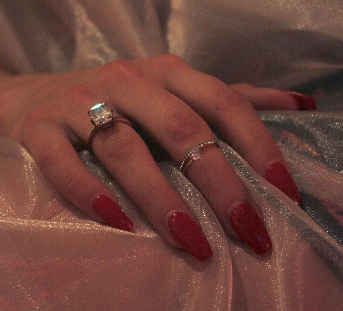 A woman wearing red nail polish and rings - Nails