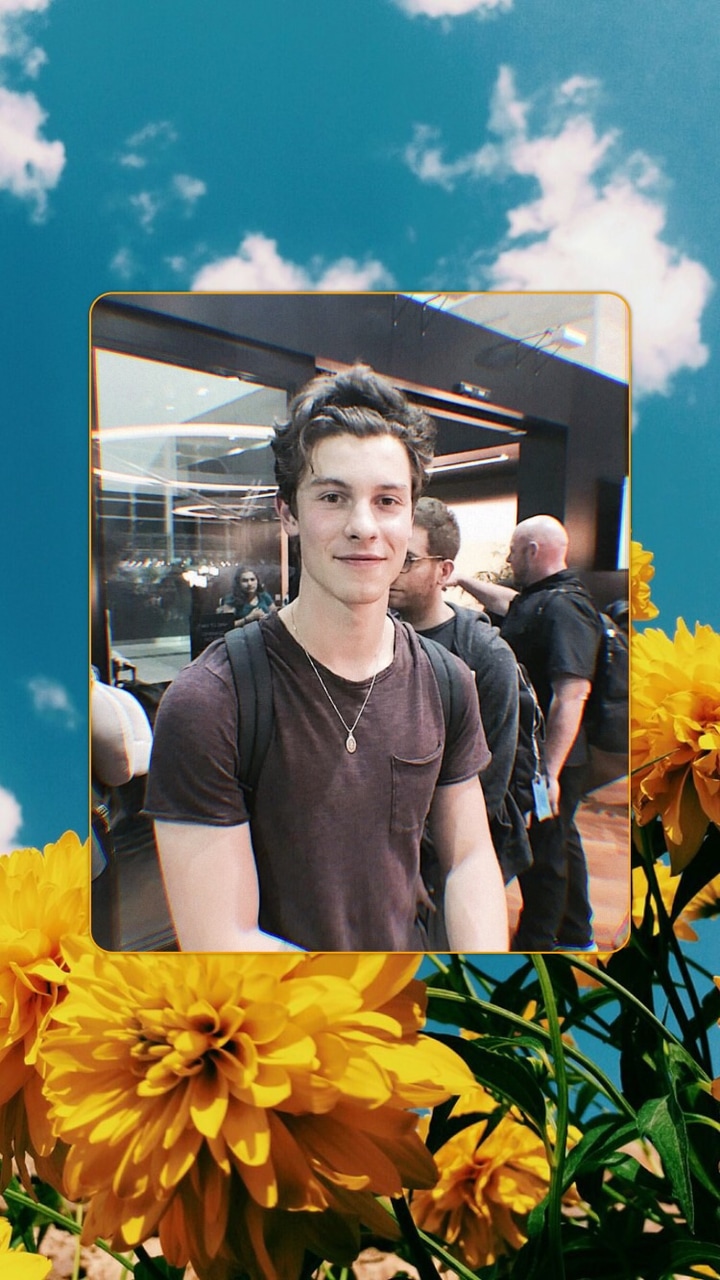 A man standing in front of some flowers - Shawn Mendes