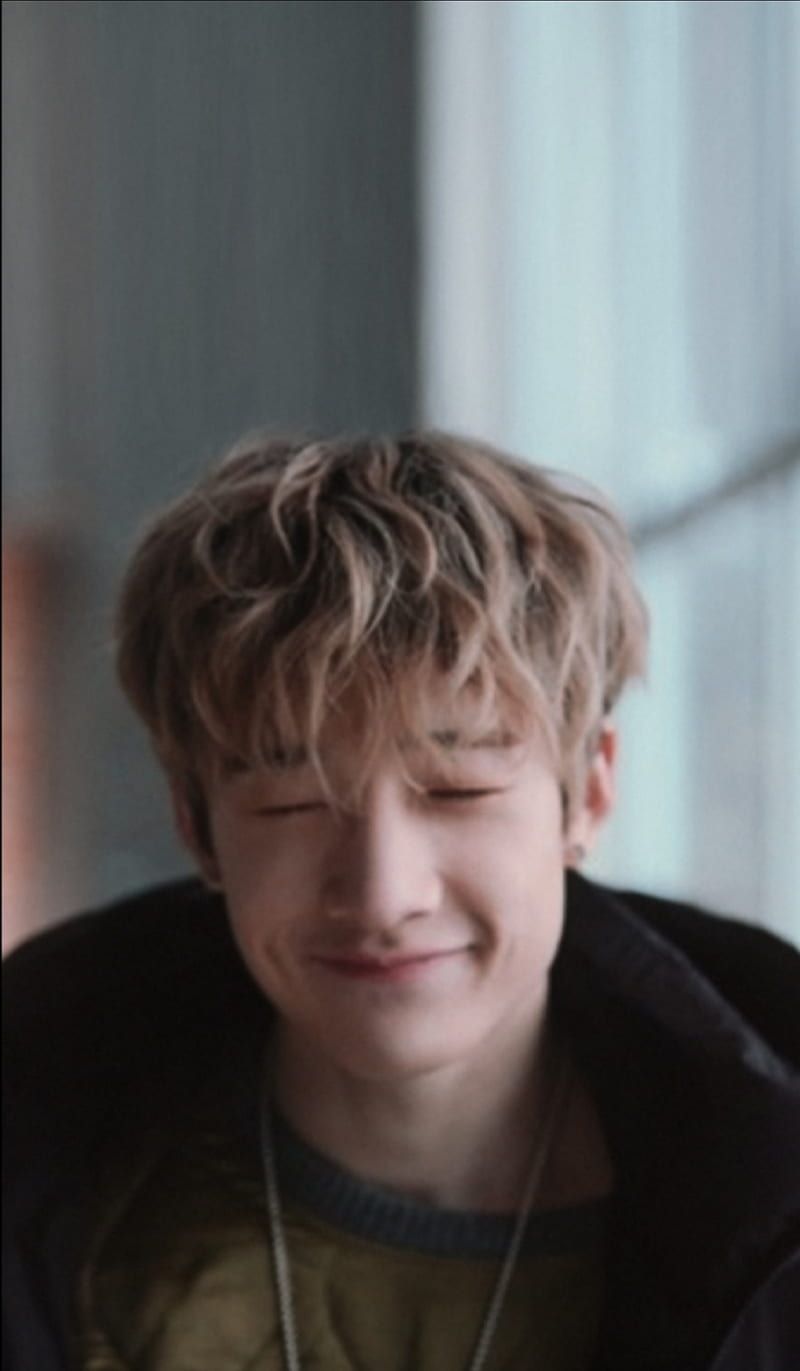 A young man with curly hair smiling - Bang Chan