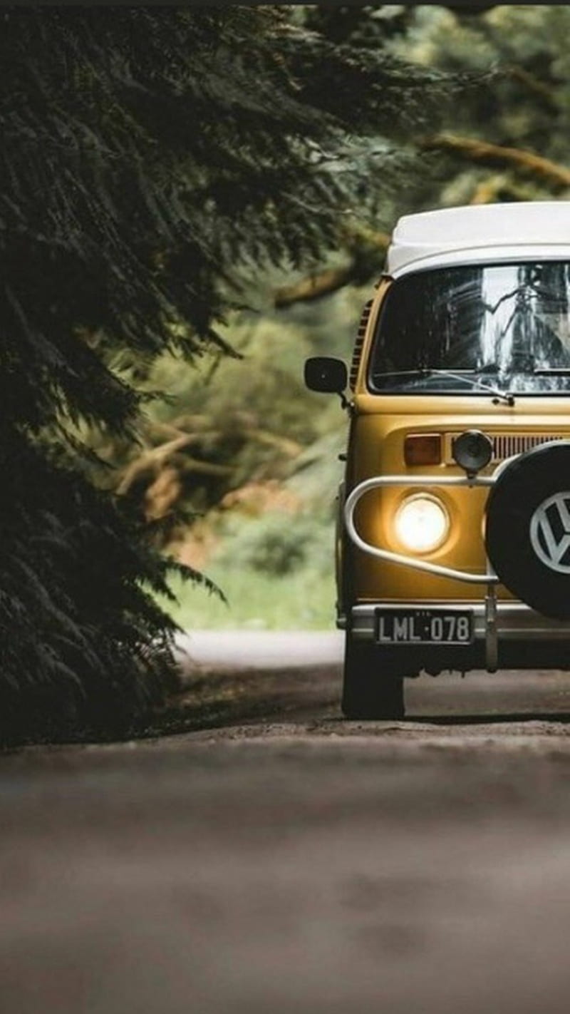 A yellow vw bus driving down the road - Camping