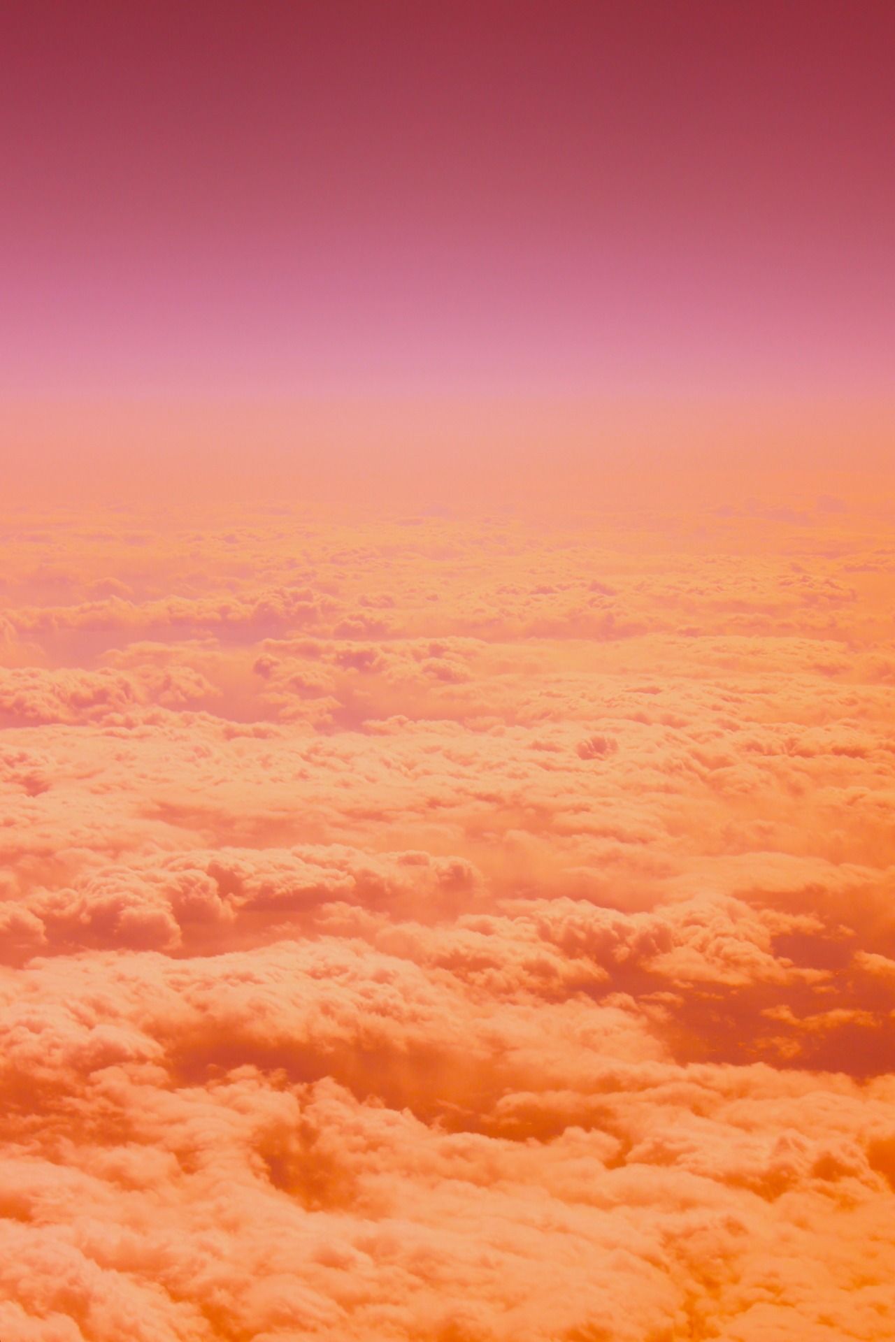 A plane flying over the clouds in an orange sky - Orange