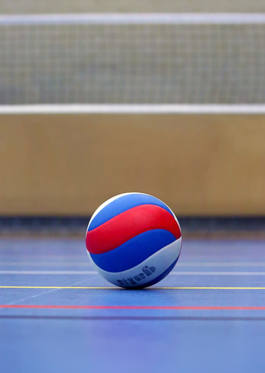 A volleyball on the court in front of the net - Volleyball