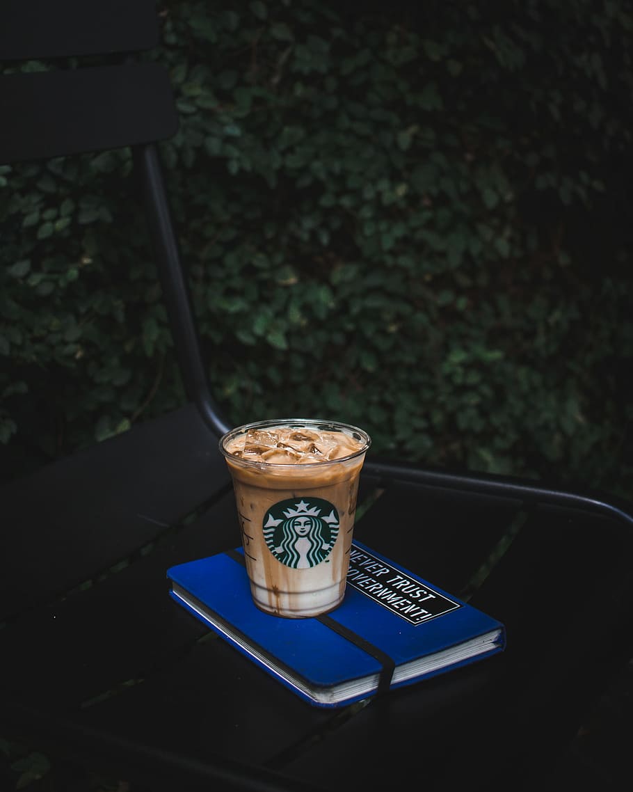 A cup of Starbucks coffee on top of a blue notebook - Starbucks, coffee