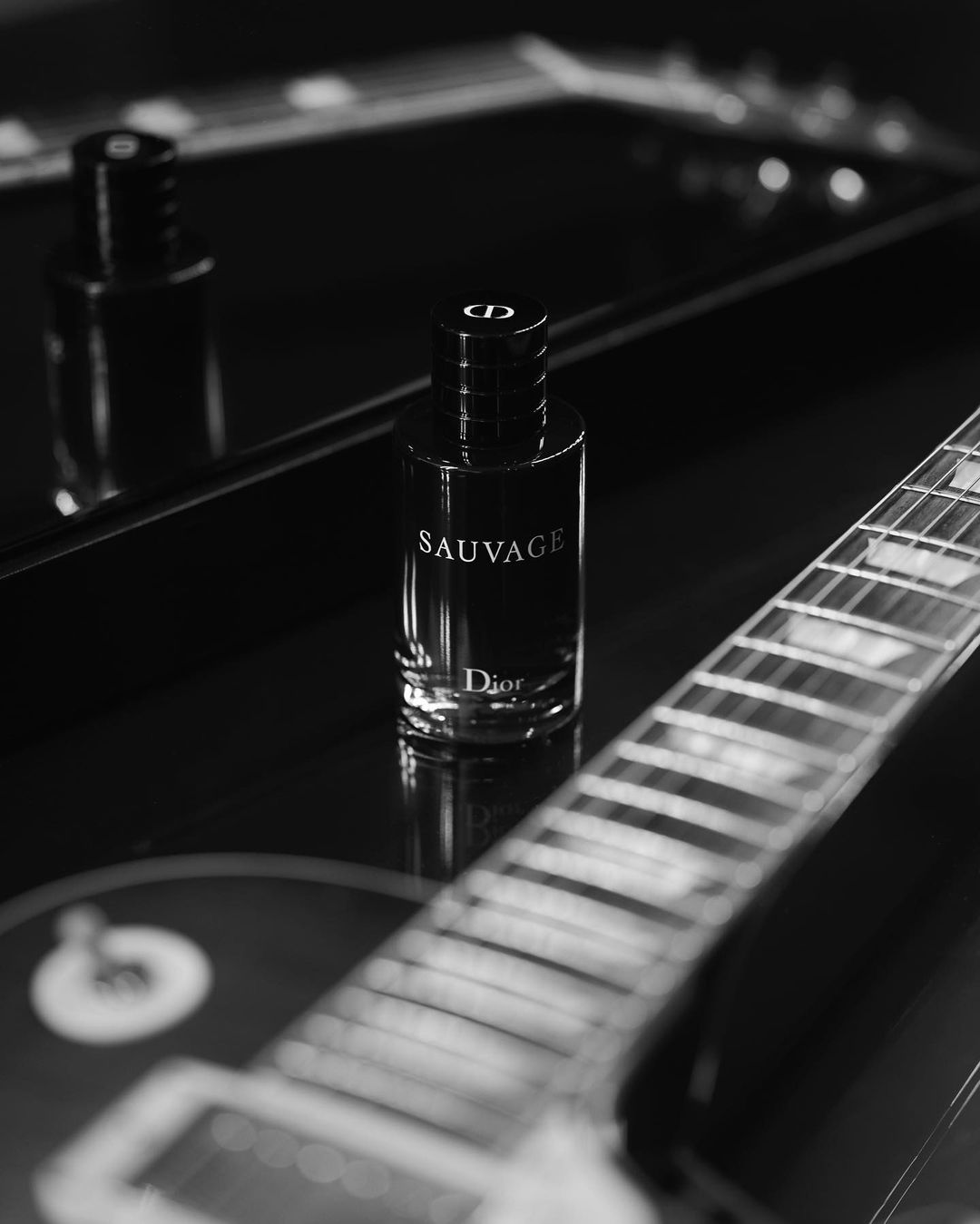A bottle of Sauvage perfume by Dior next to a guitar - Dior