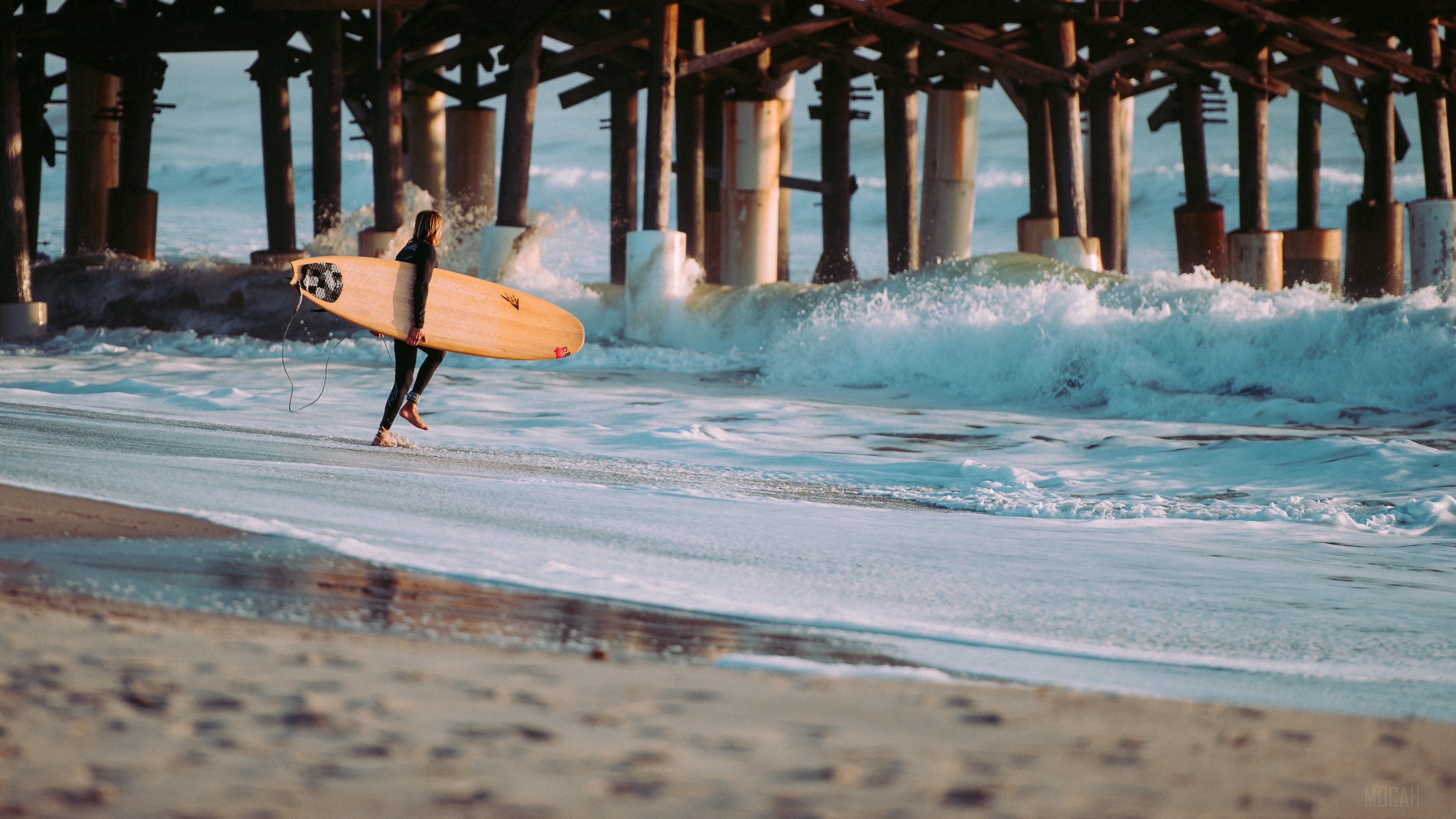 A man carrying a surfboard out of the ocean. - Surf