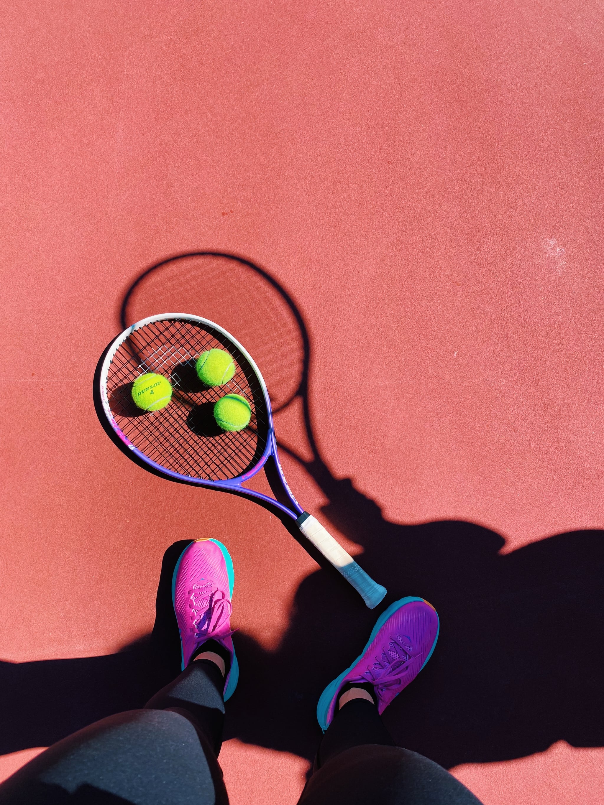 A person standing on top of tennis court with racket and balls - Tennis