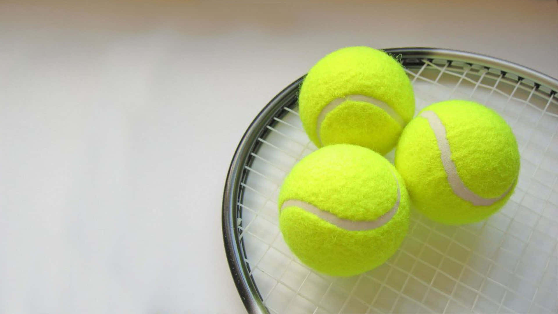 A tennis racket with three tennis balls on it - Tennis