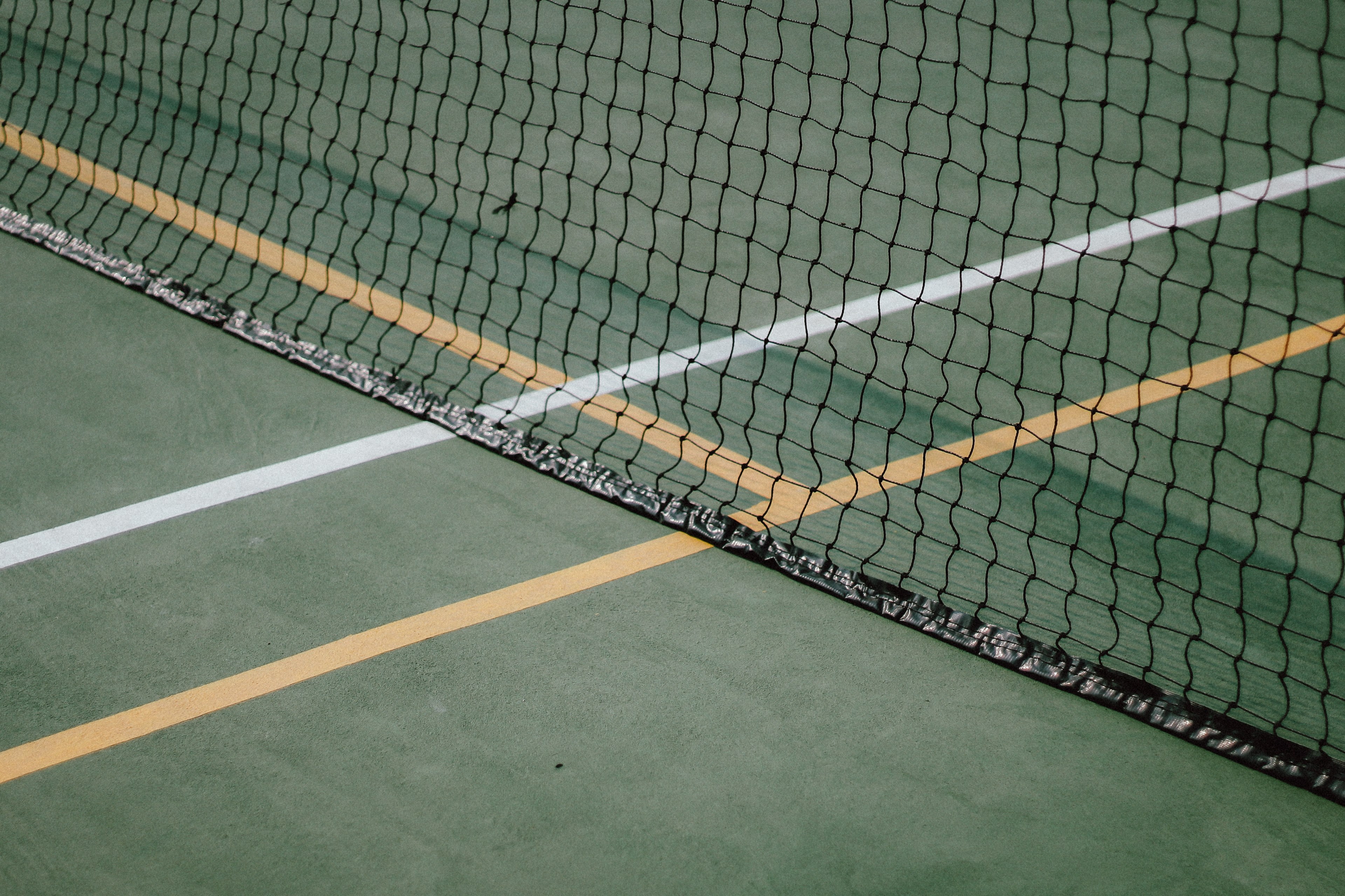 A tennis net with a green floor - Tennis