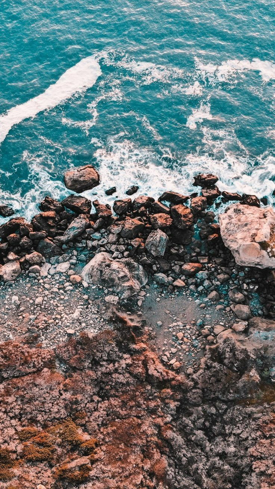 A rocky shore with waves crashing against it - Calming