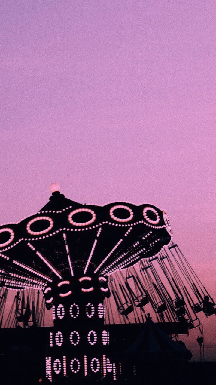 A carousel with pink and purple hues in the sky. - California