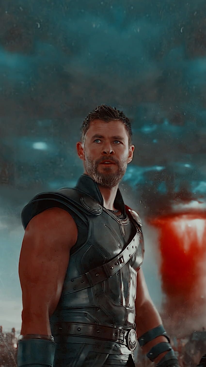 A man in armor standing next to an explosion - Thor