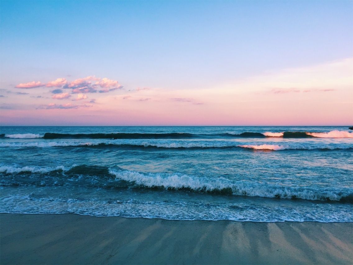 A beach with waves and sand at sunset - Beach