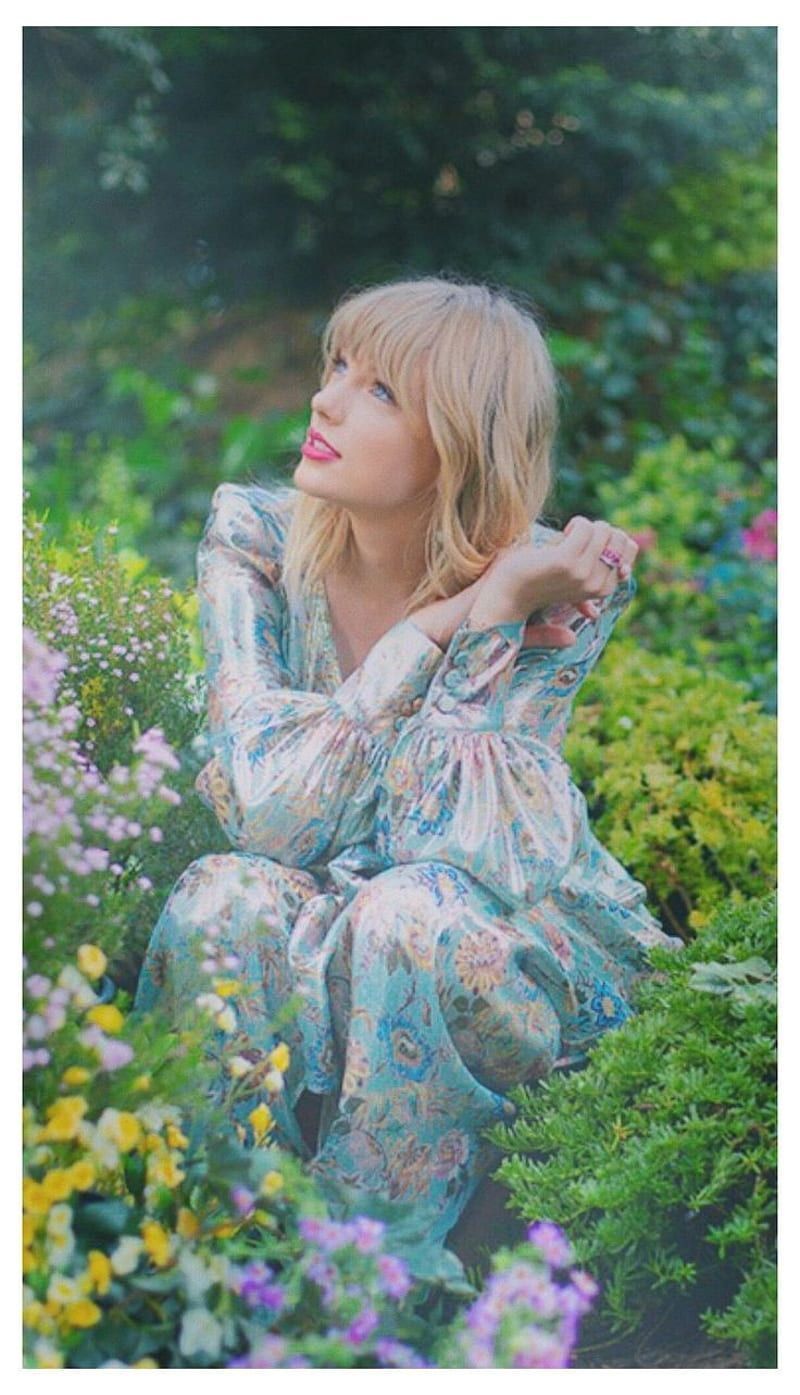 Taylor Swift in a floral dress sitting in a garden - Taylor Swift