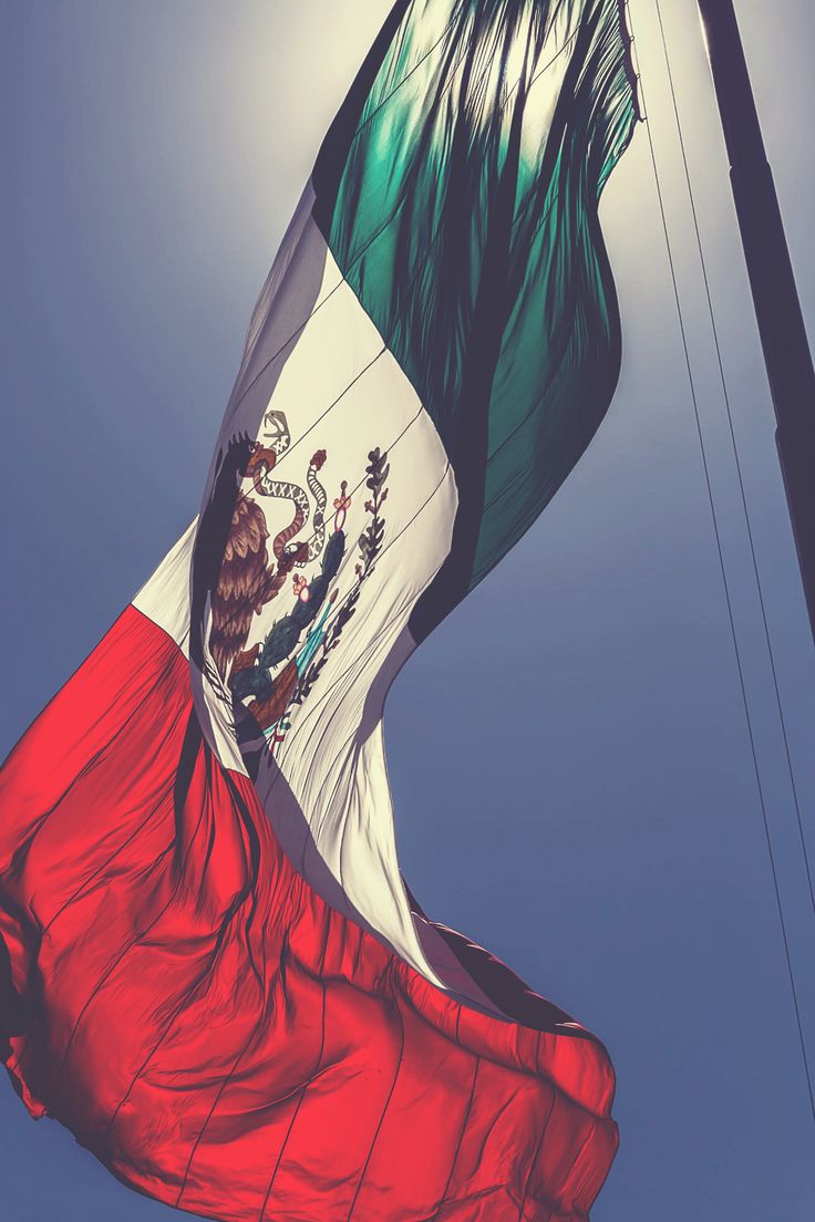 A Mexican flag waves in the wind on a sunny day. - Mexico