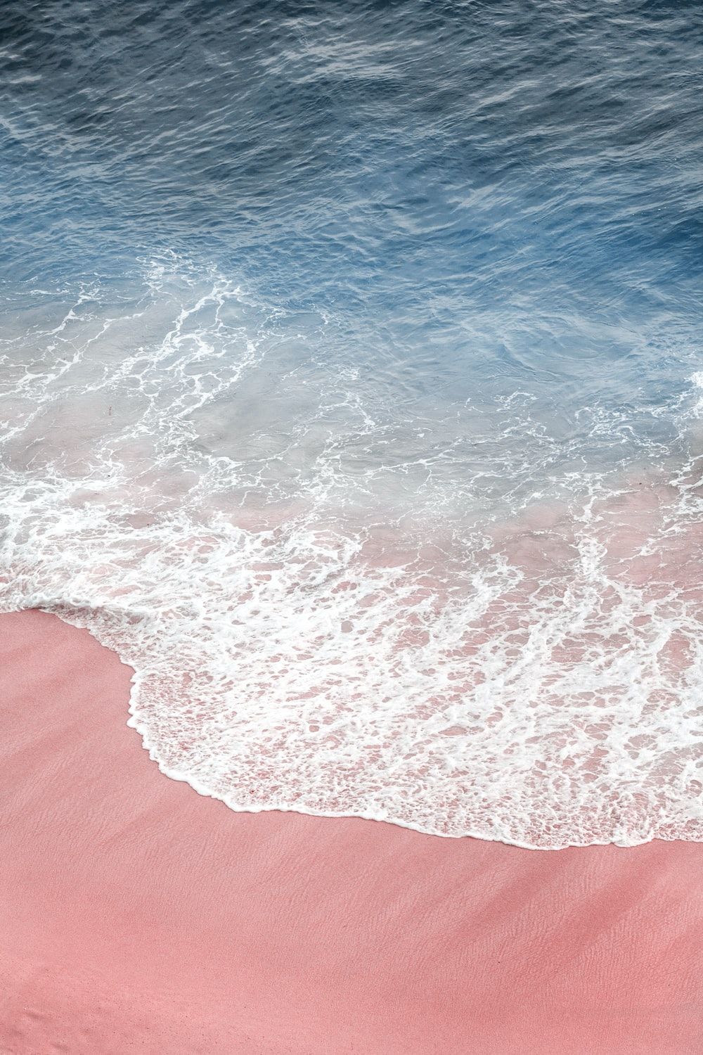 A pink and blue beach with waves crashing - Beach