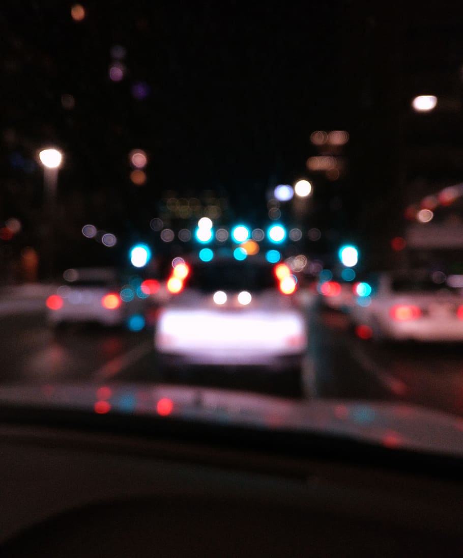 A blurry image of a car driving down a city street at night. - Blurry