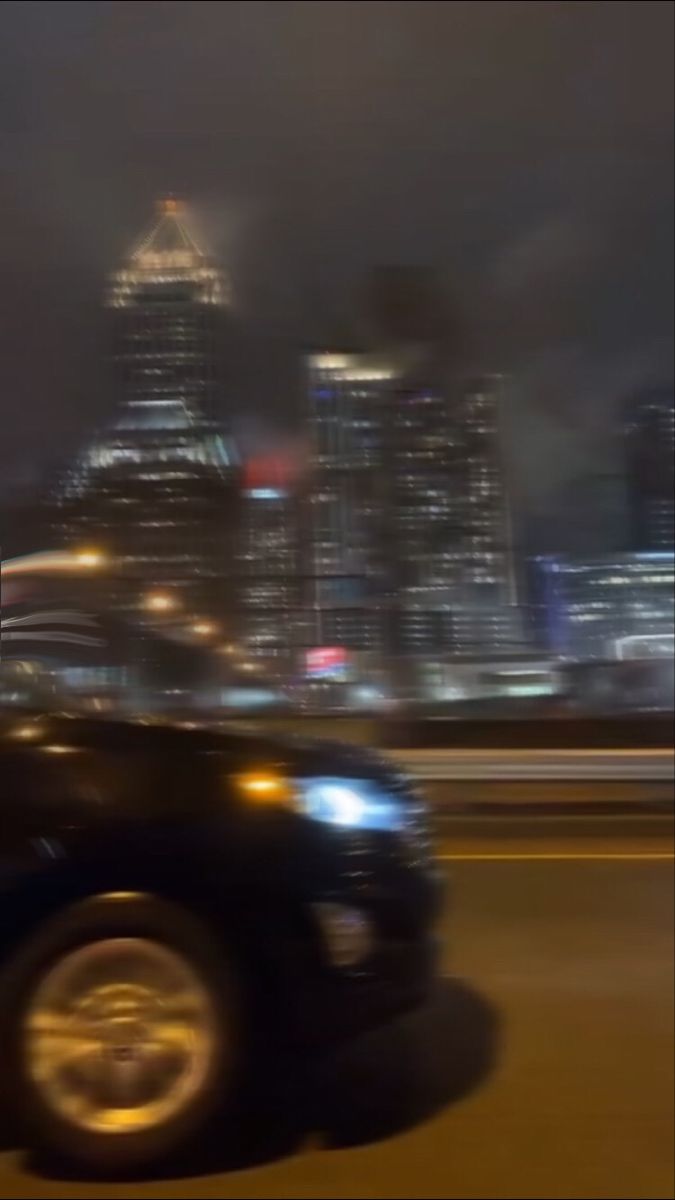 A blurry car driving down a road with a blurry city in the background. - Blurry