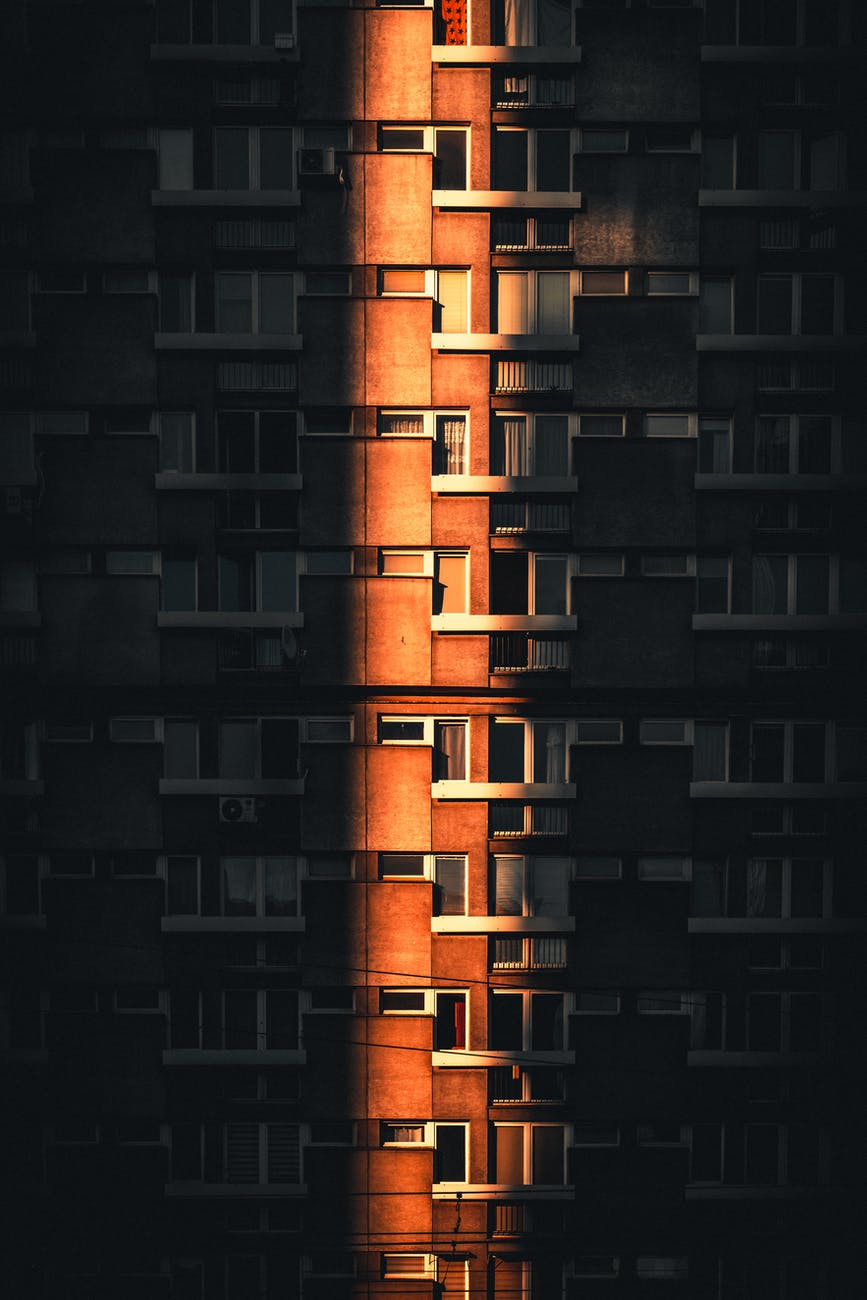 A vertical photo of a tall building with windows and a door. - Architecture