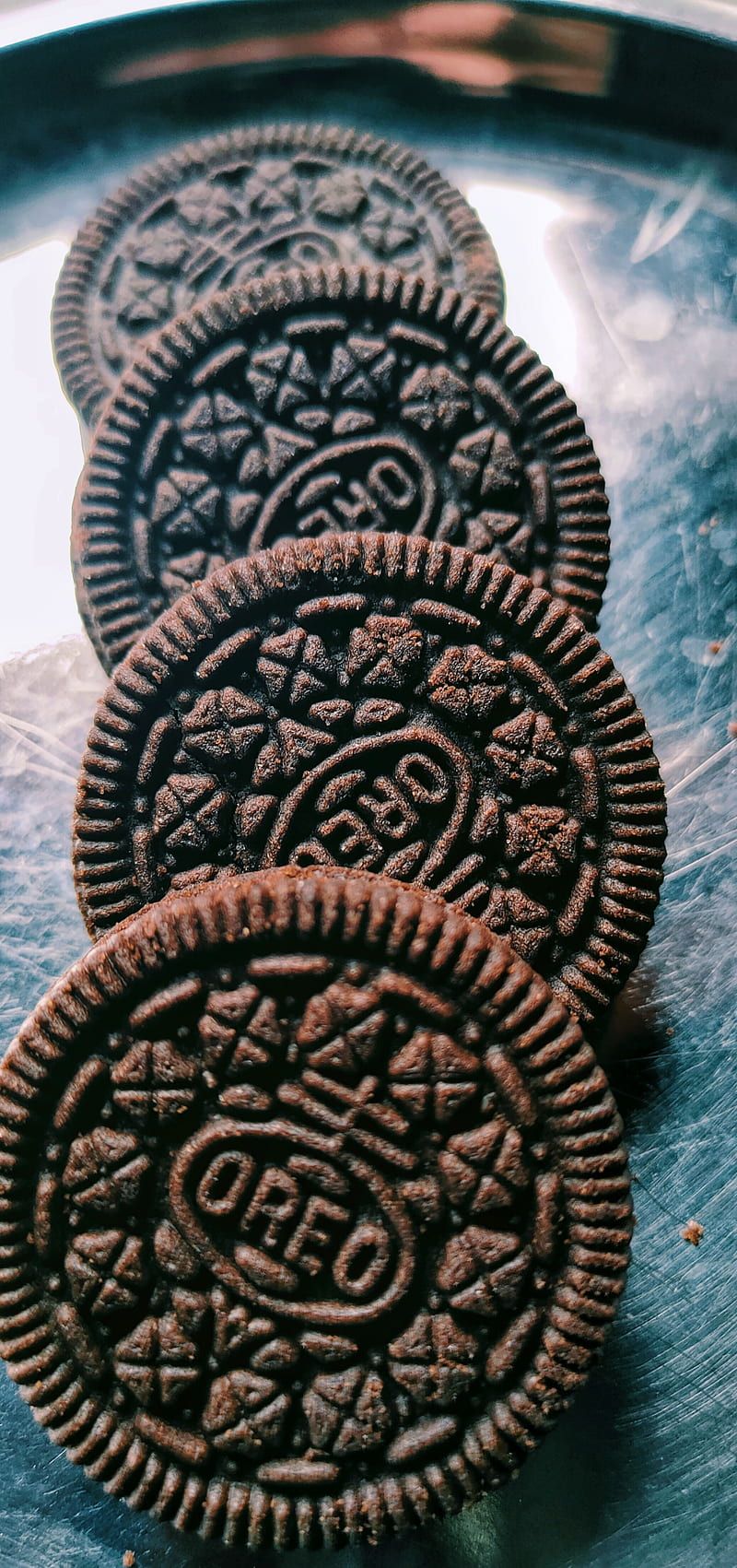 Four chocolate sandwich cookies on a metal tray. - Oreo