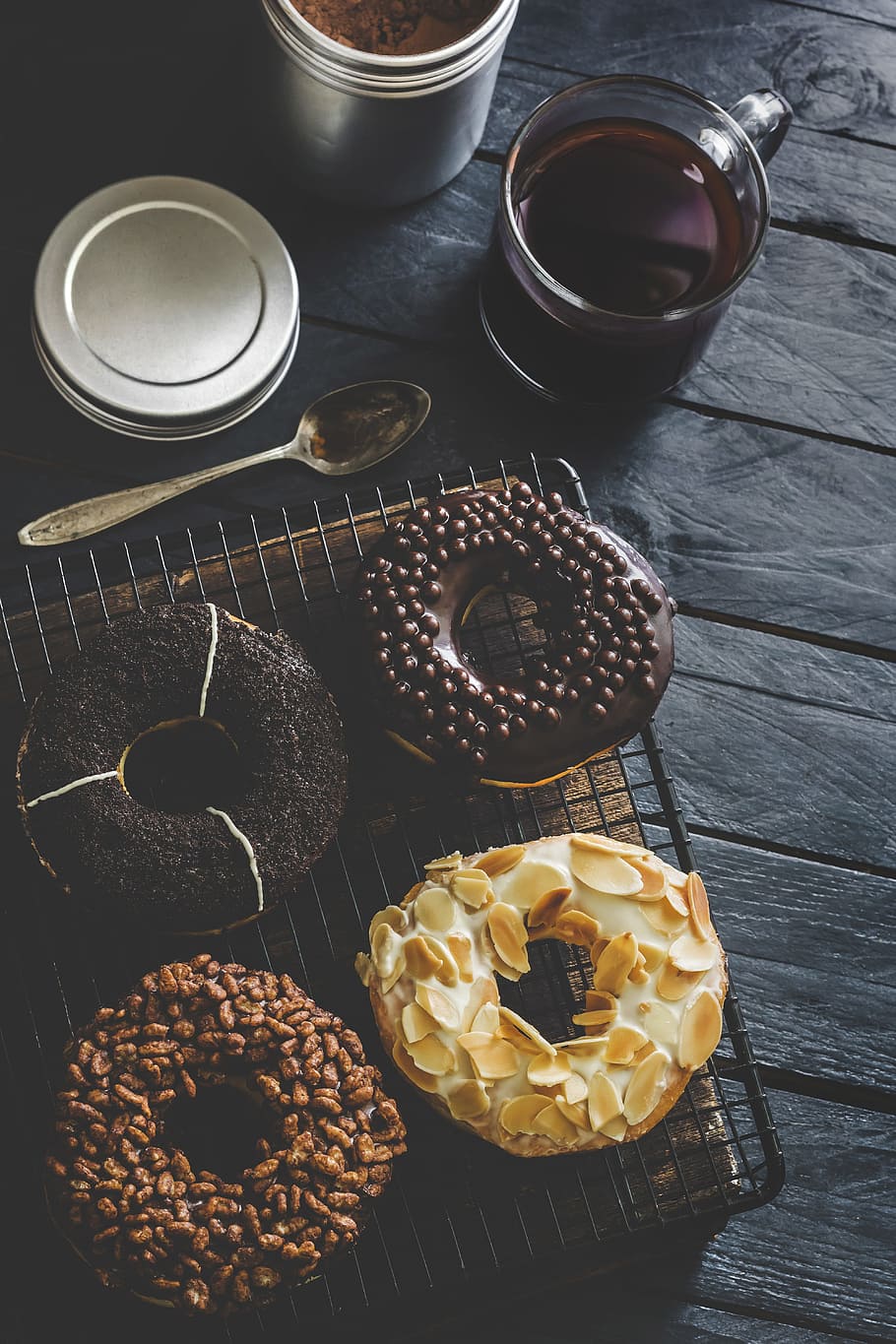 A selection of donuts on a cooling rack next to a cup of coffee. - Oreo