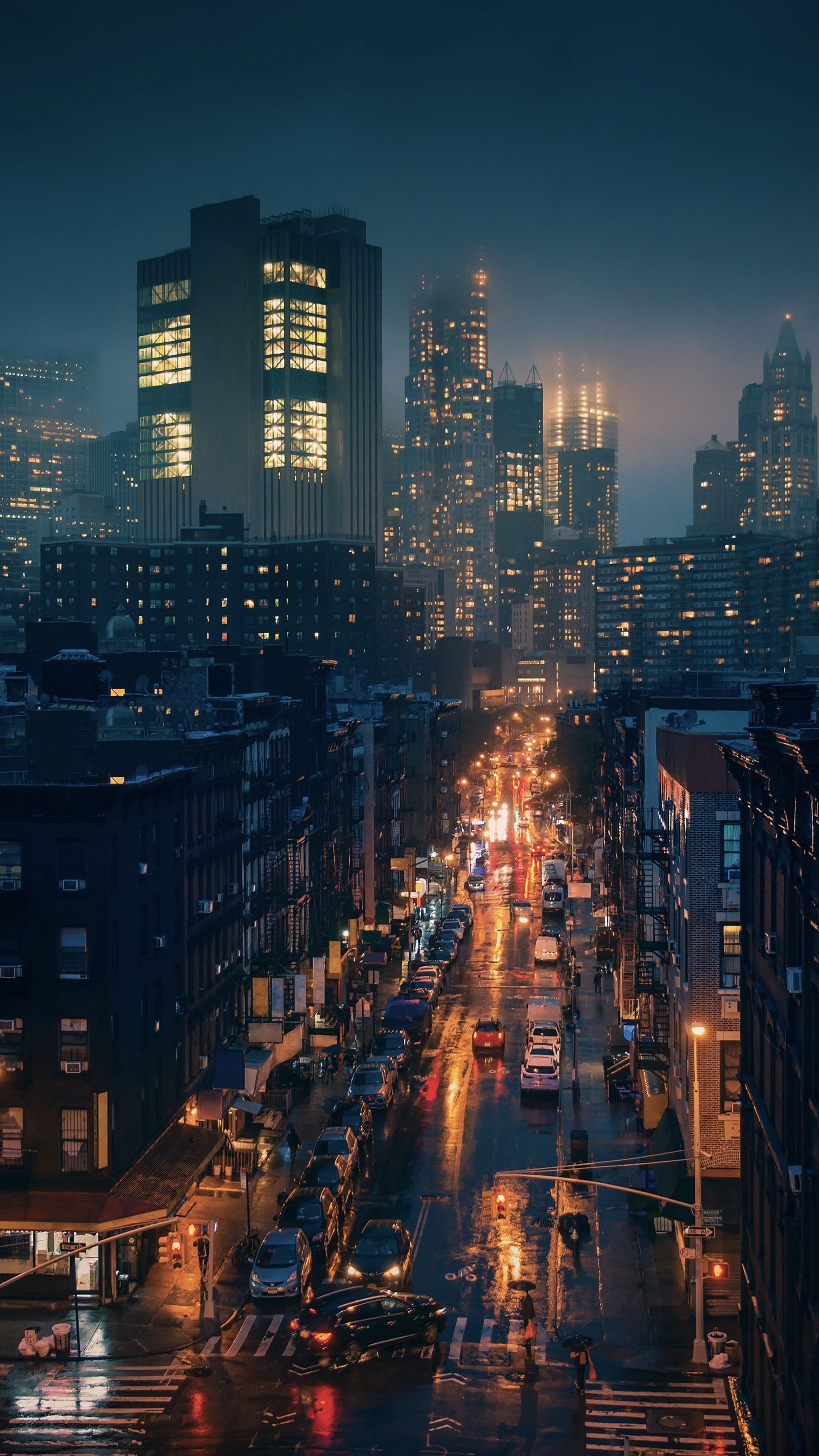 A city street at night with tall buildings lit up in the background - City