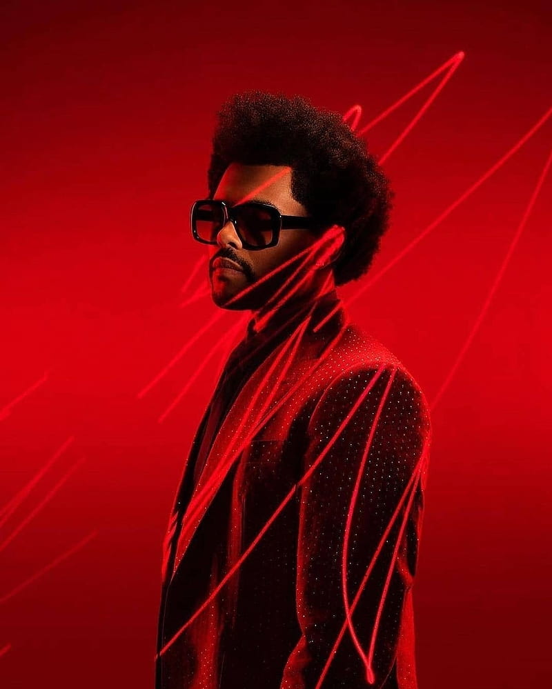 The Weeknd in a suit and sunglasses, with a red background and red laser lights around him - The Weeknd