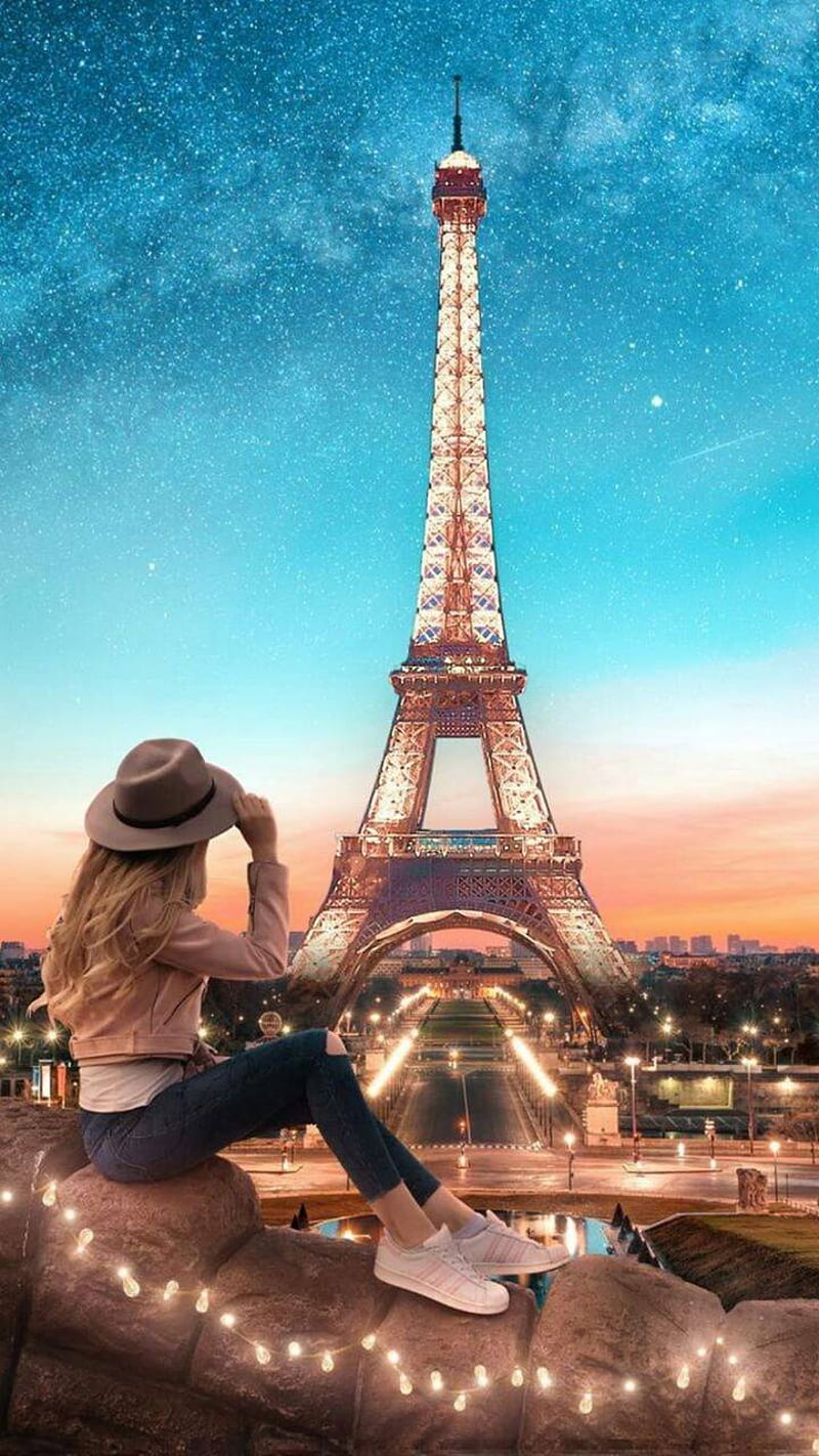 A woman sitting on the edge of an eiffel tower - Paris