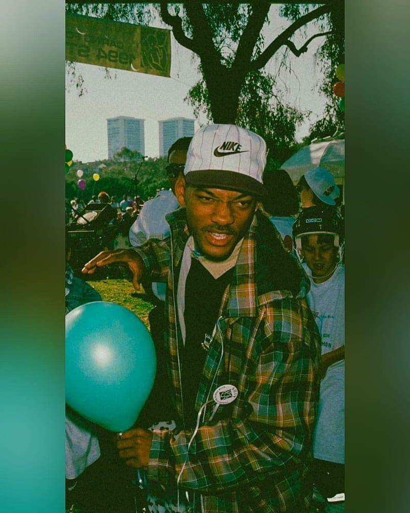 A man in plaid shirt holding a blue balloon. - 90s