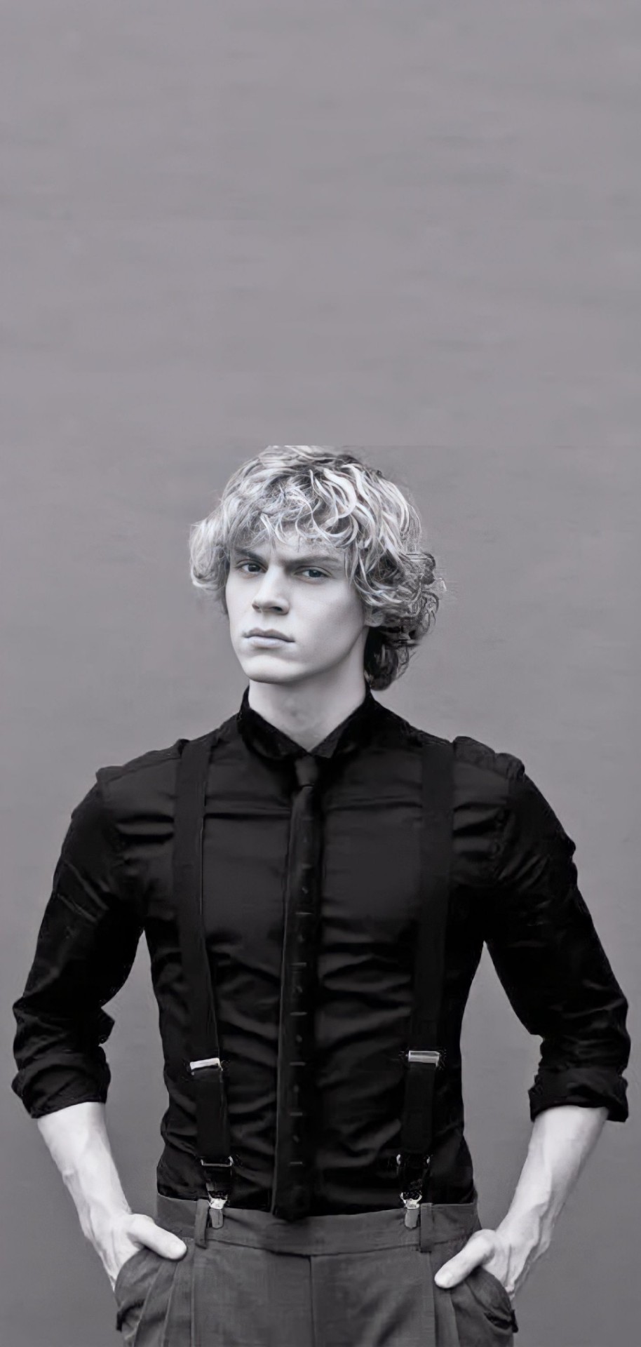 A man in suspenders and shirt standing - Evan Peters