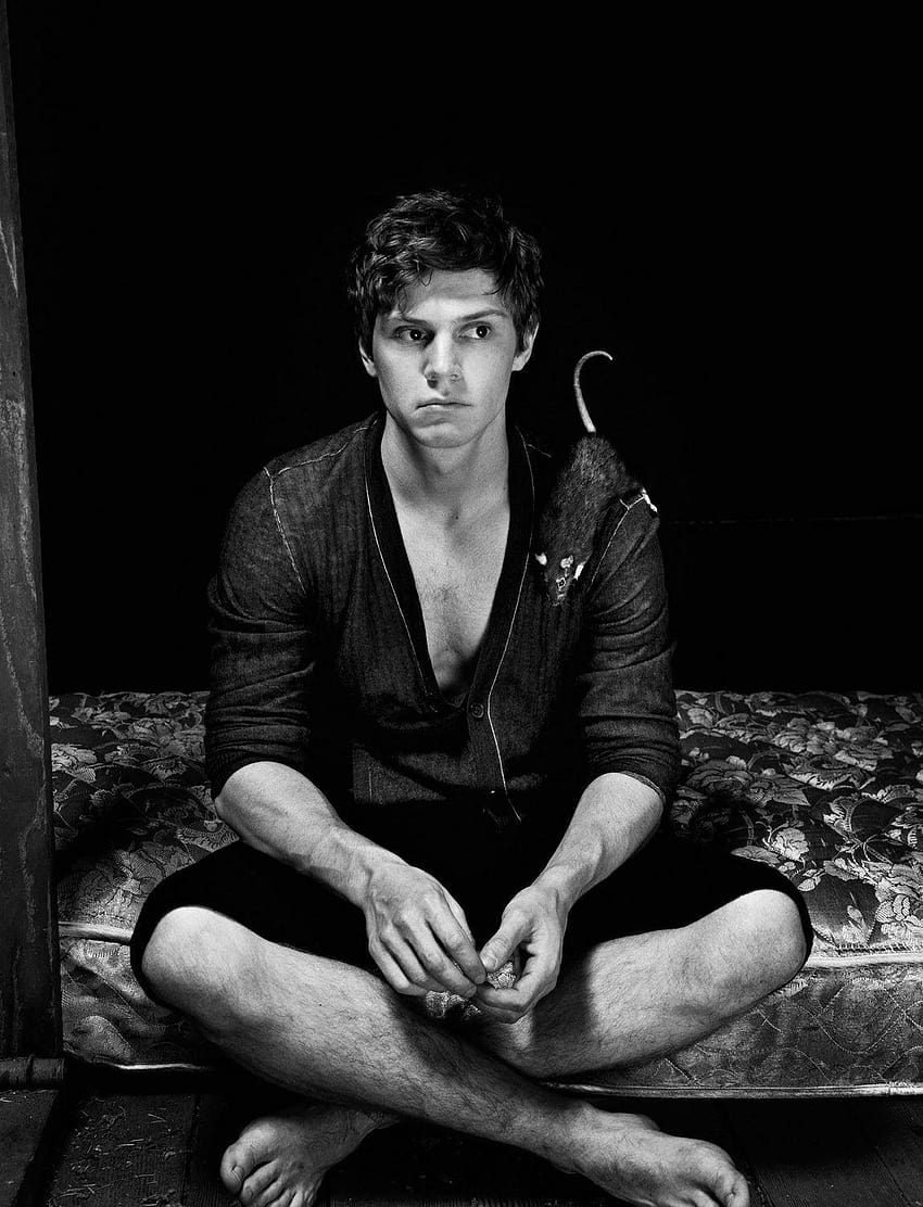 A man sitting on a bed with a black background - Evan Peters