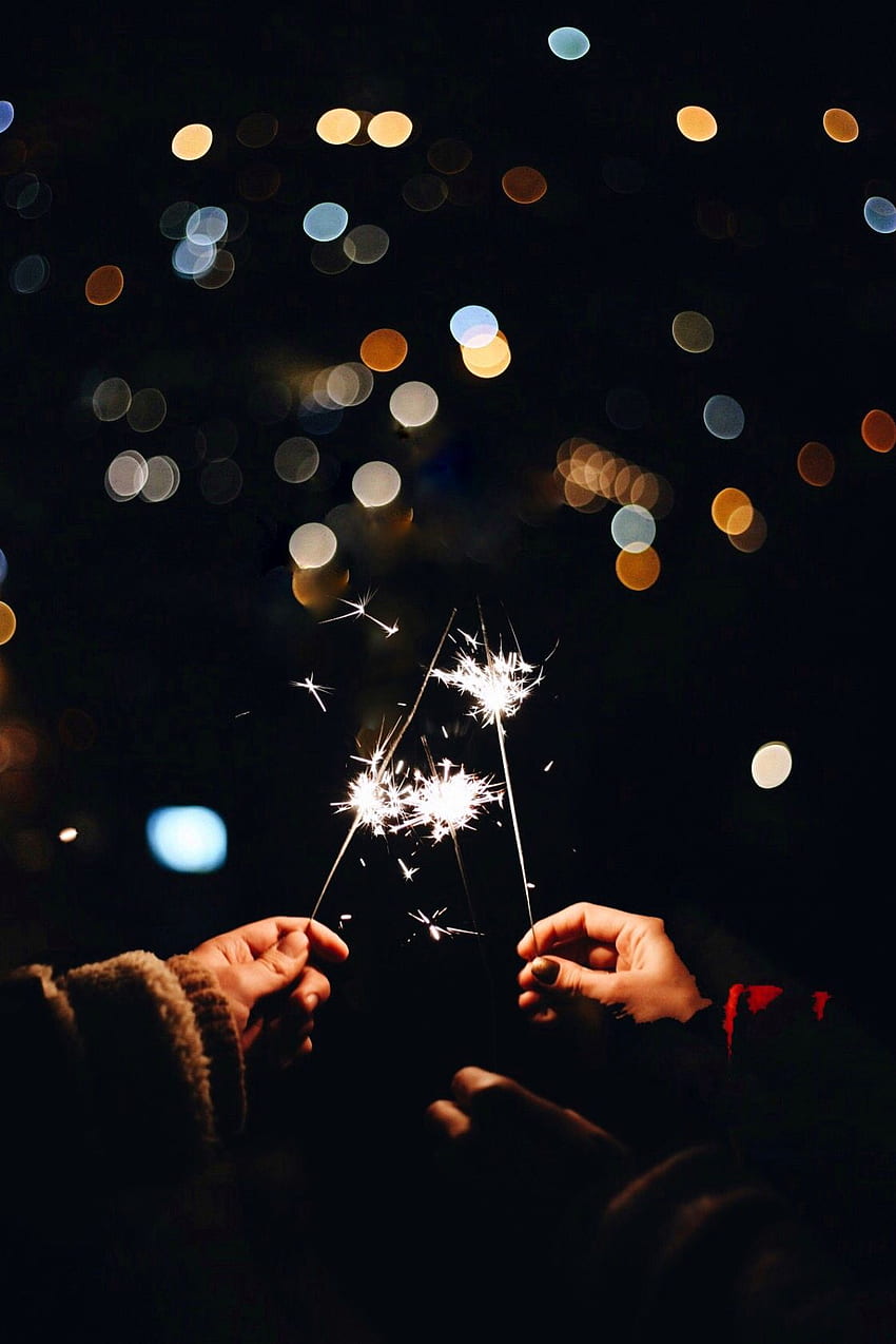 Two people holding sparklers in the dark - New Year