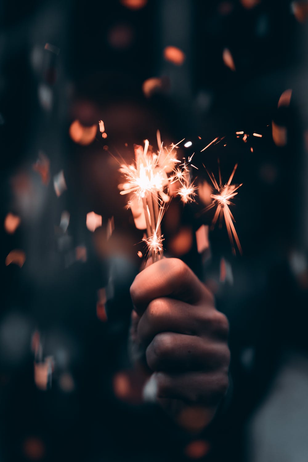A person holding a sparkler in their hand. - New Year