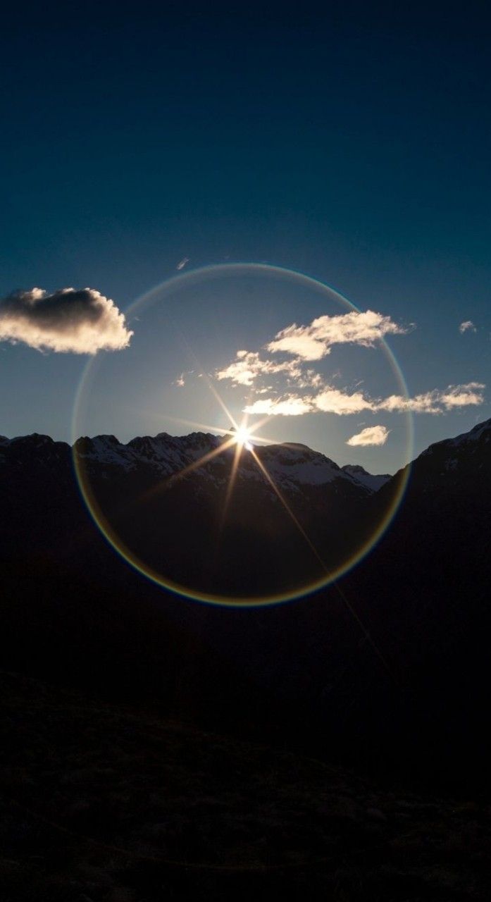 A circular sun glare with a mountain range in the background - Sunshine, sunlight