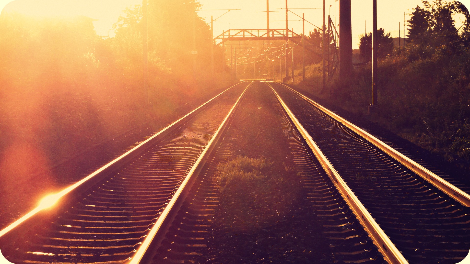 A train track is shown with the sun shining on it. - Sunshine