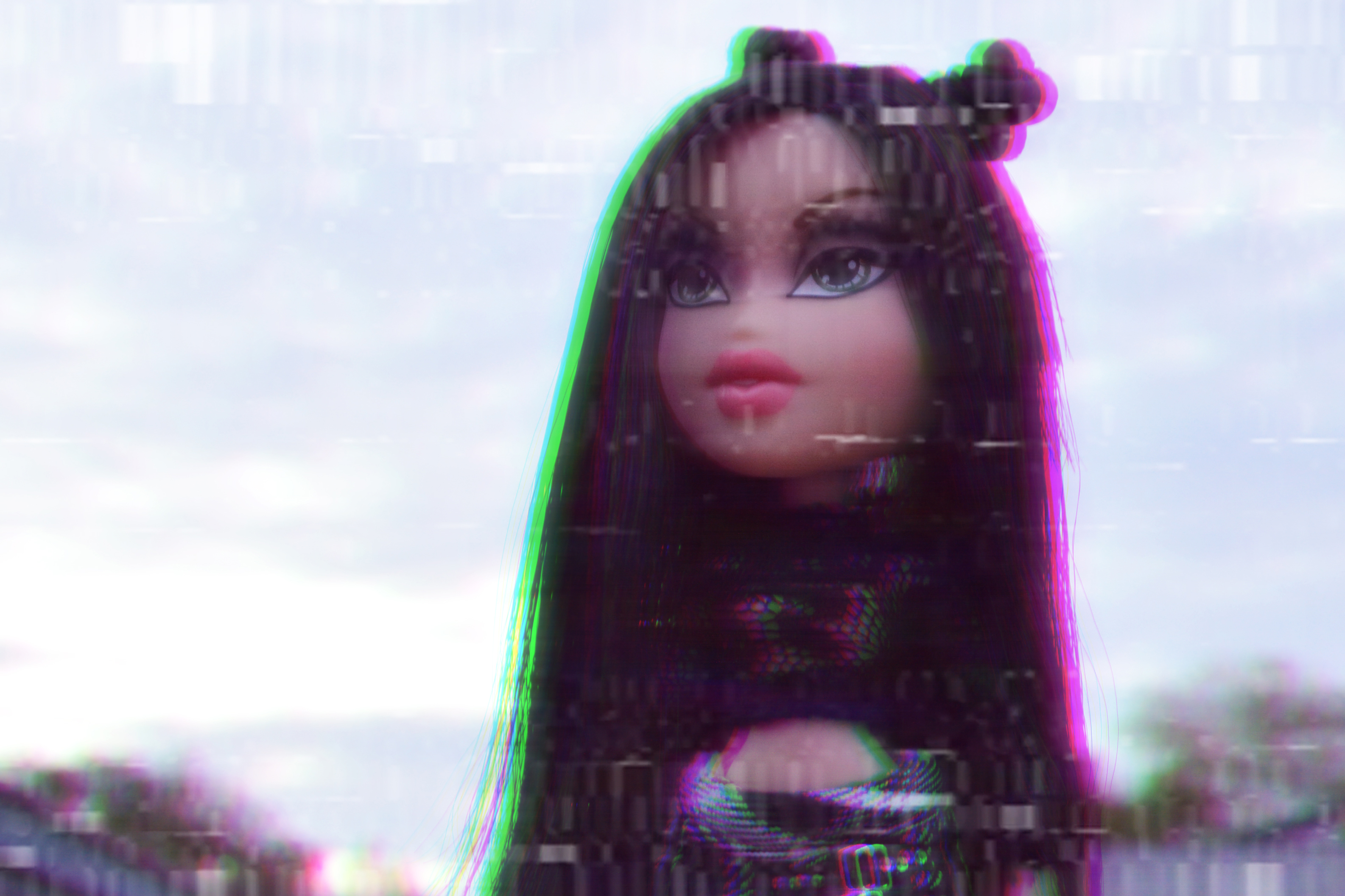 A doll with long black hair and a black top with a pink and green glow around it. - Barbie