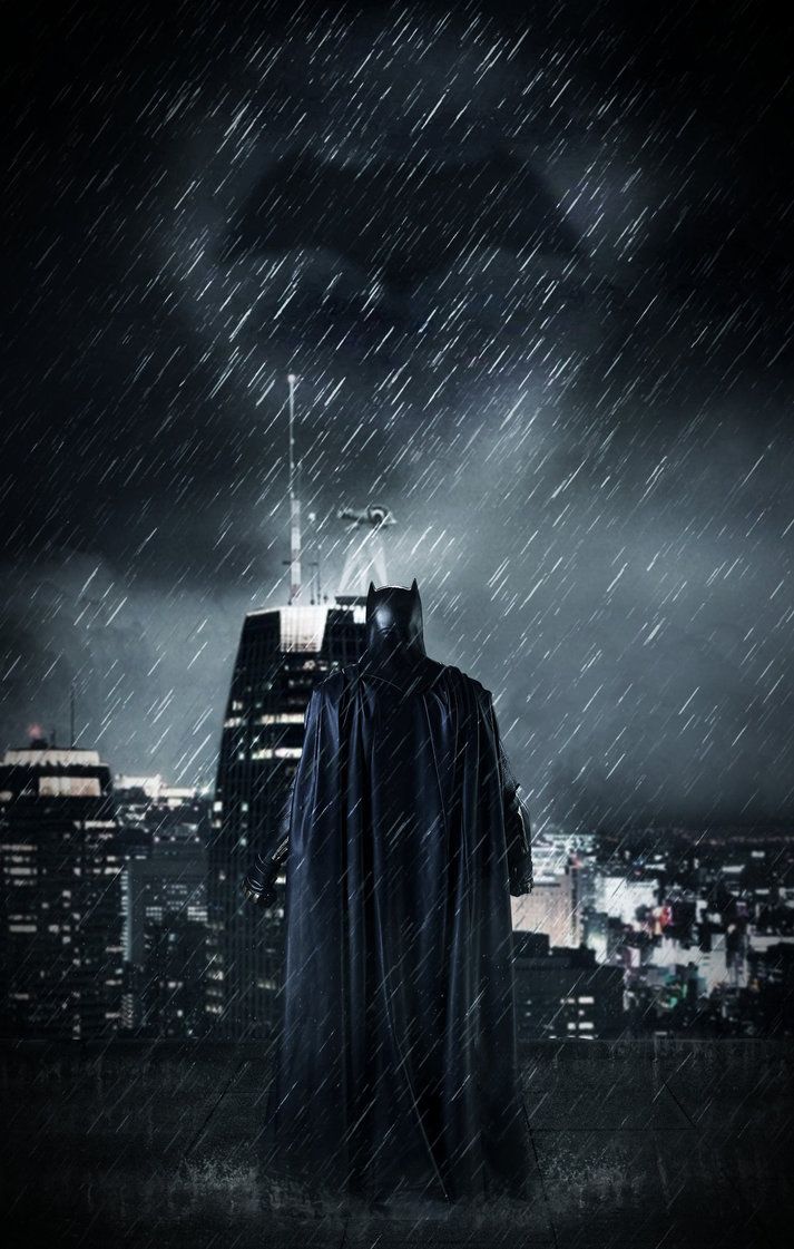 A batman standing on a rooftop looking out over a city at night - Batman