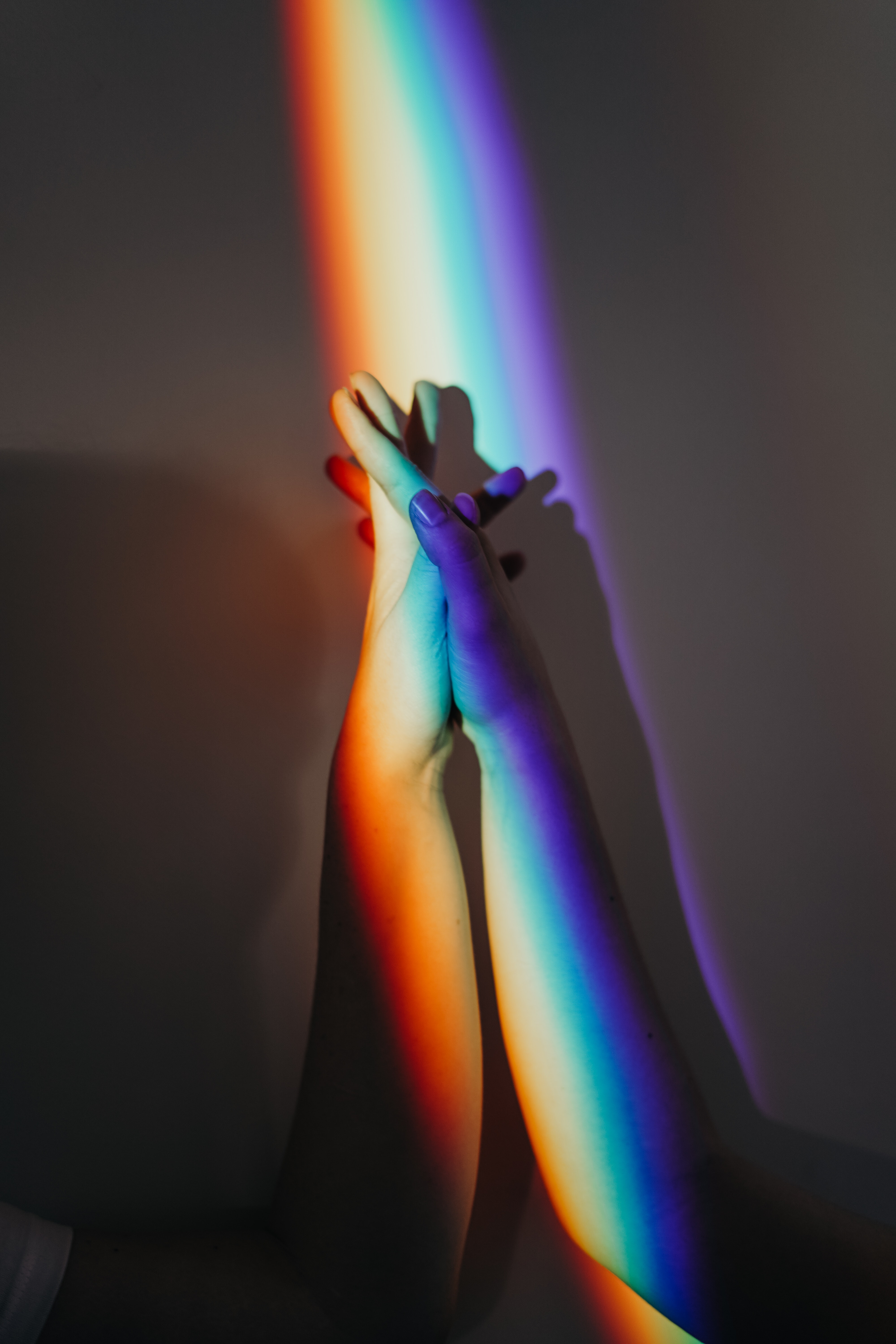 A person's hands are shown against a rainbow colored background. - LGBT