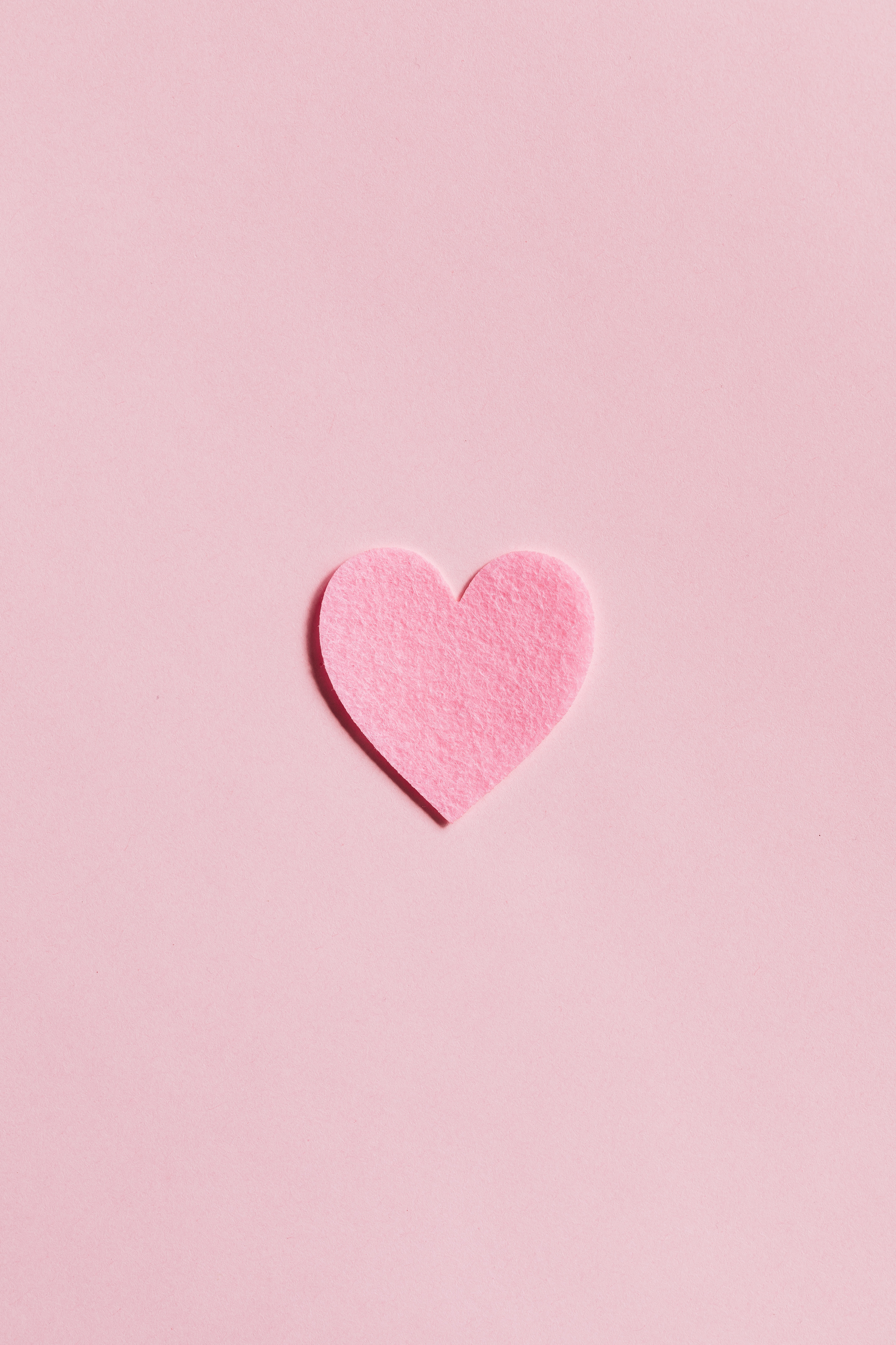 A pink heart shaped paper on top of some light colored background - Heart