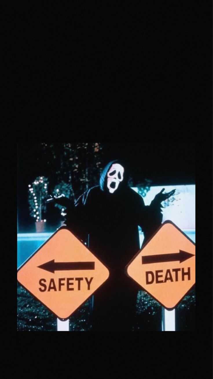 A man in a white mask with a knife behind a sign that says safety and death. - Ghostface