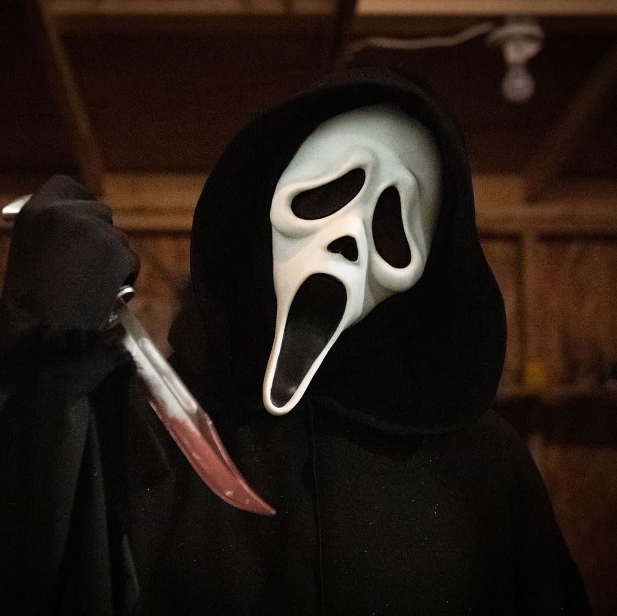 A man in a white ghostface mask is holding a knife. - Ghostface