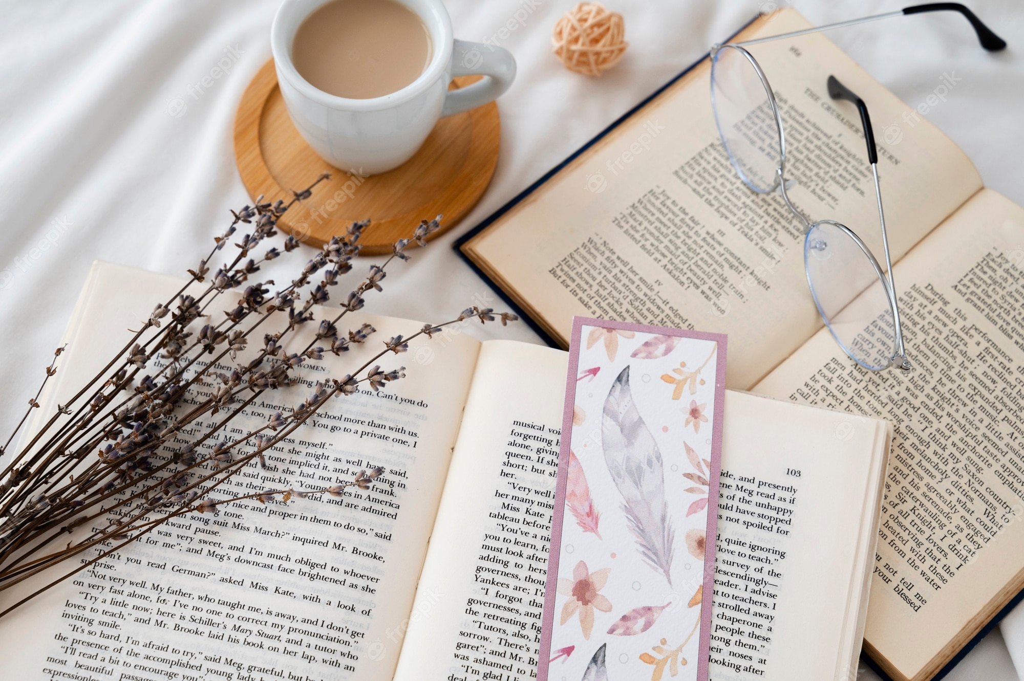 A book, a bookmark, a pair of glasses and a cup of coffee on a white bed sheet - Books