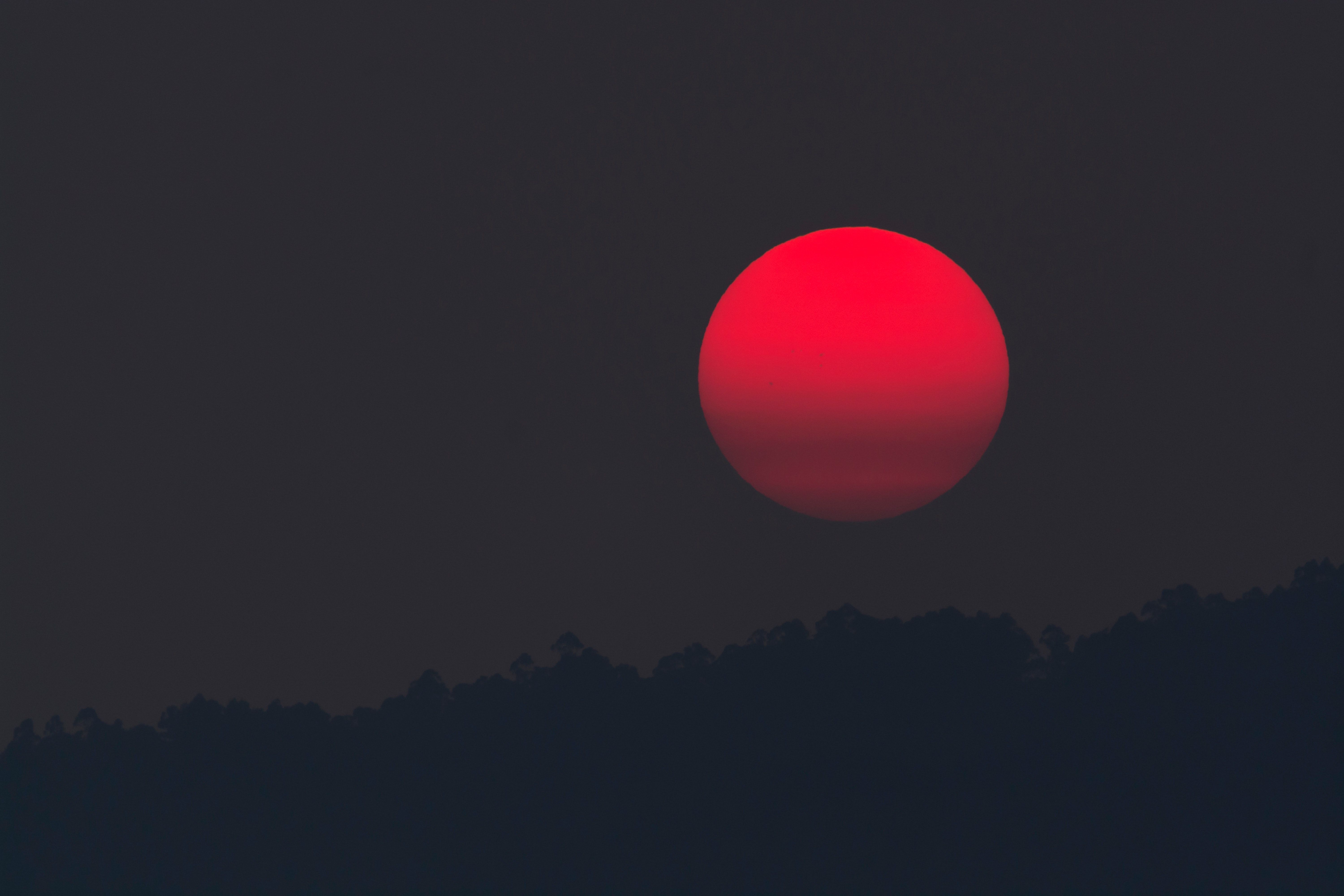 A red sun setting behind trees and mountains - YouTube