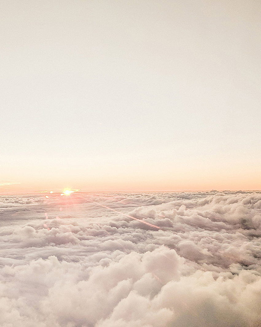 A plane flying over the clouds at sunset - Cream