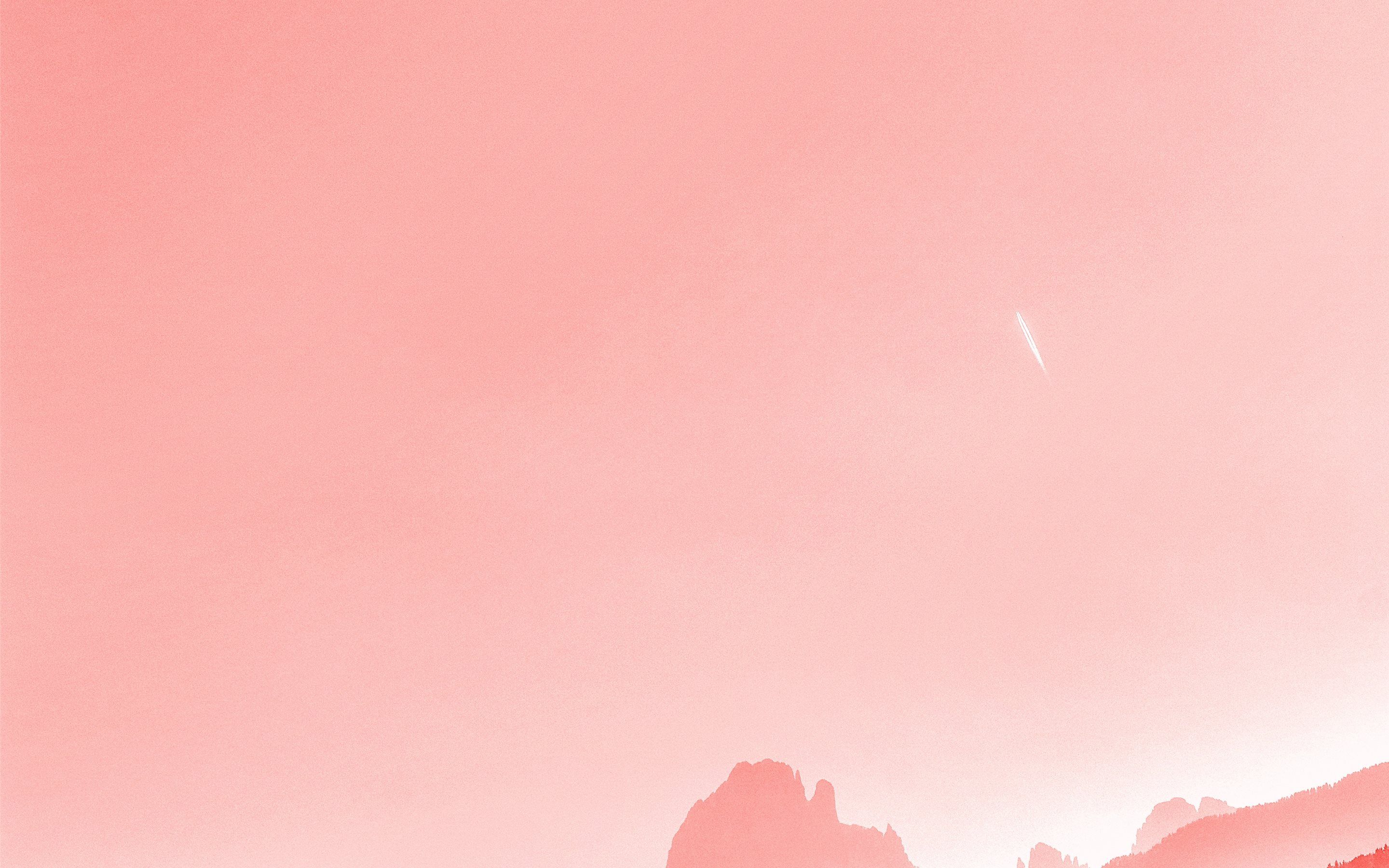 A pink sky with a shooting star over a mountain range - Coral